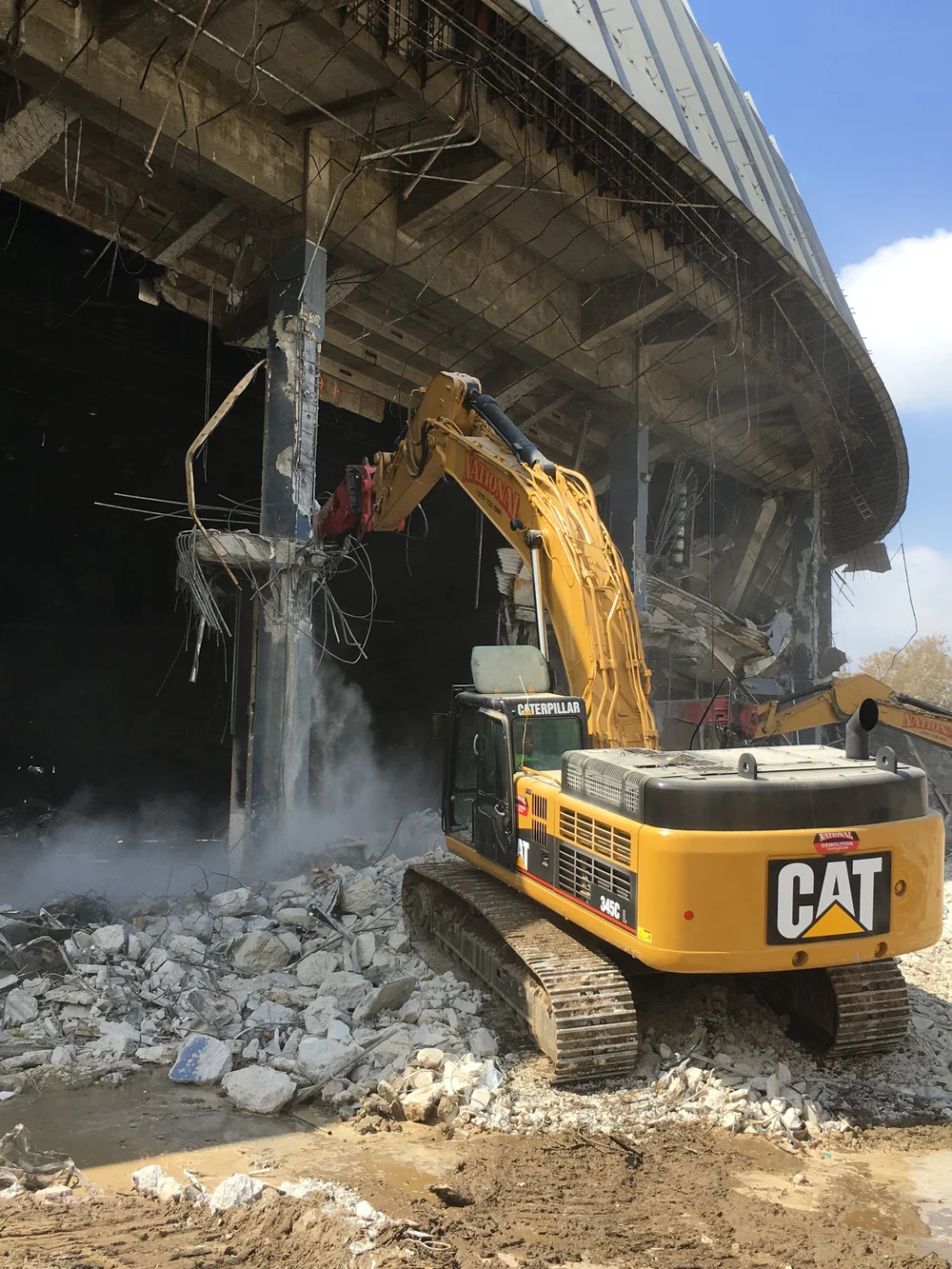 Excavator working beneath the remaining structure of a building