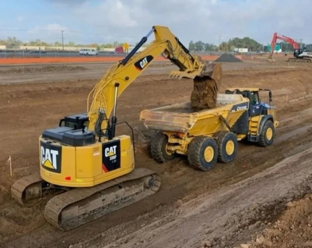 Excavator loading an articulated haul truck at an earthwork site