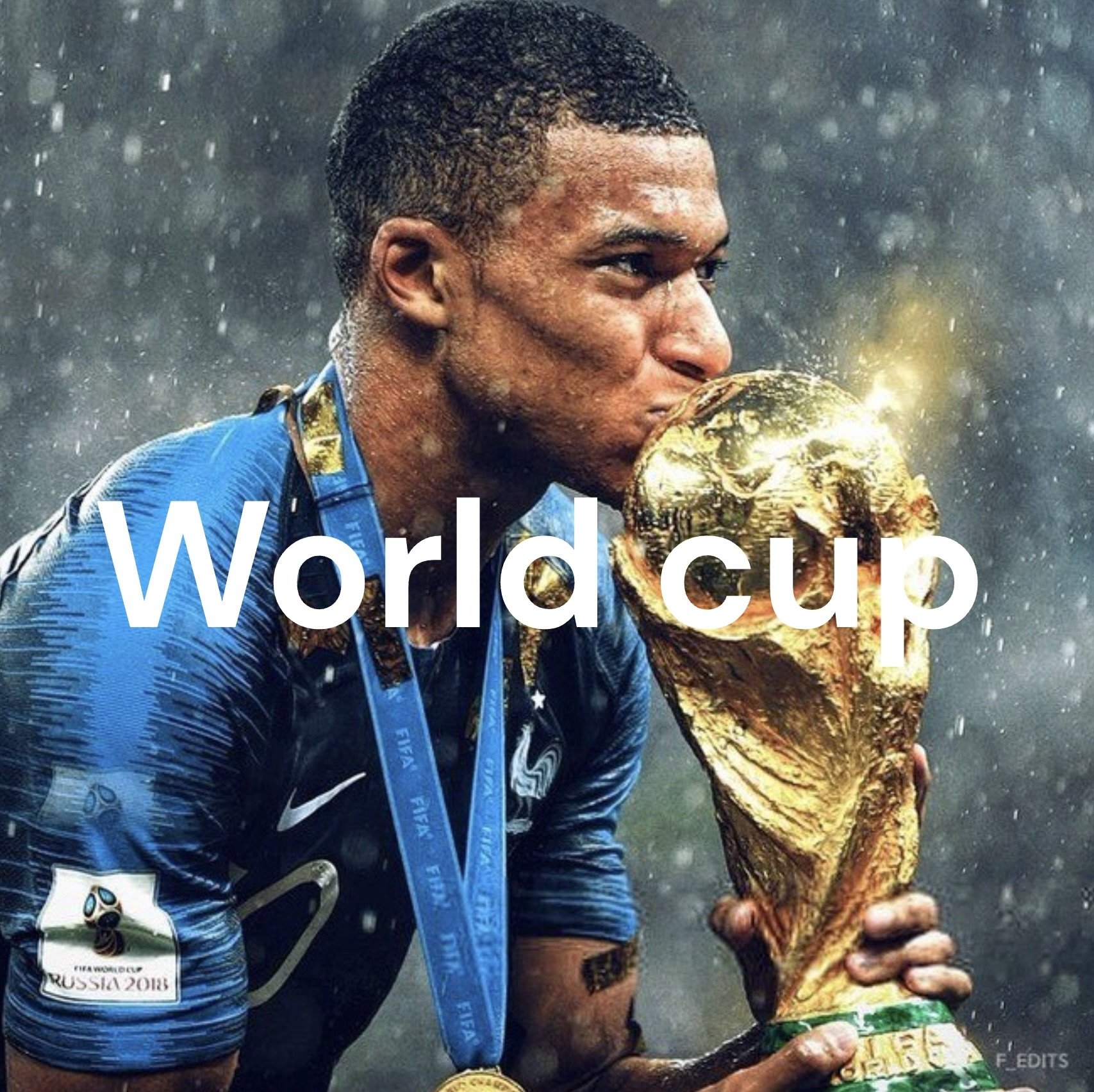 A soccer player in a blue uniform kissing the FIFA World Cup trophy after winning. The scene is rainy, and the player is wearing medals around his neck.