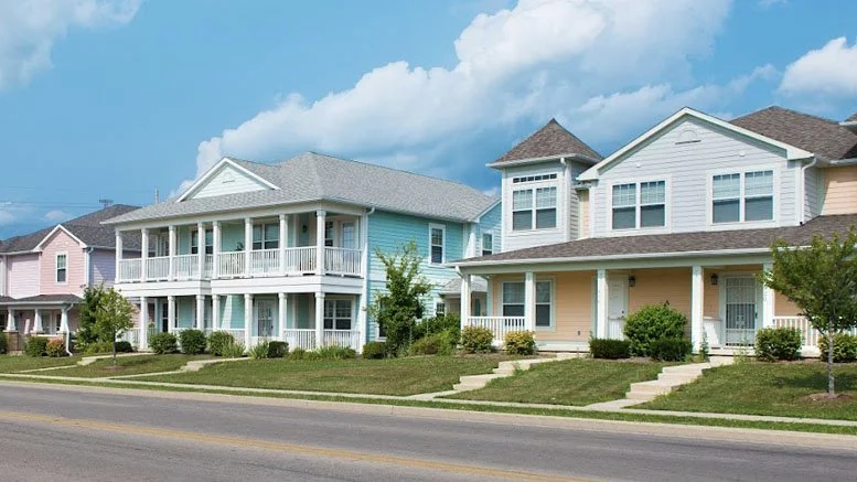 Colorful suburban houses with manicured lawns on a sunny day