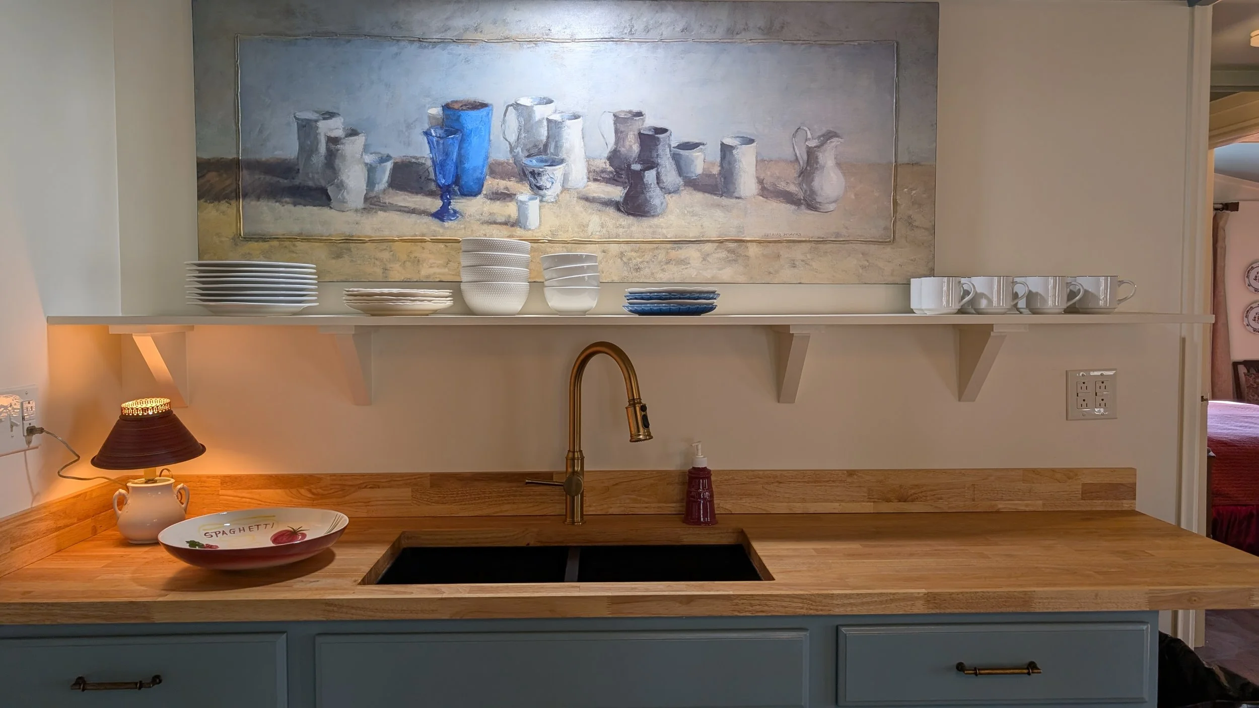 Butcher block countertops, modern black sink, brass fixtures and original artwork.