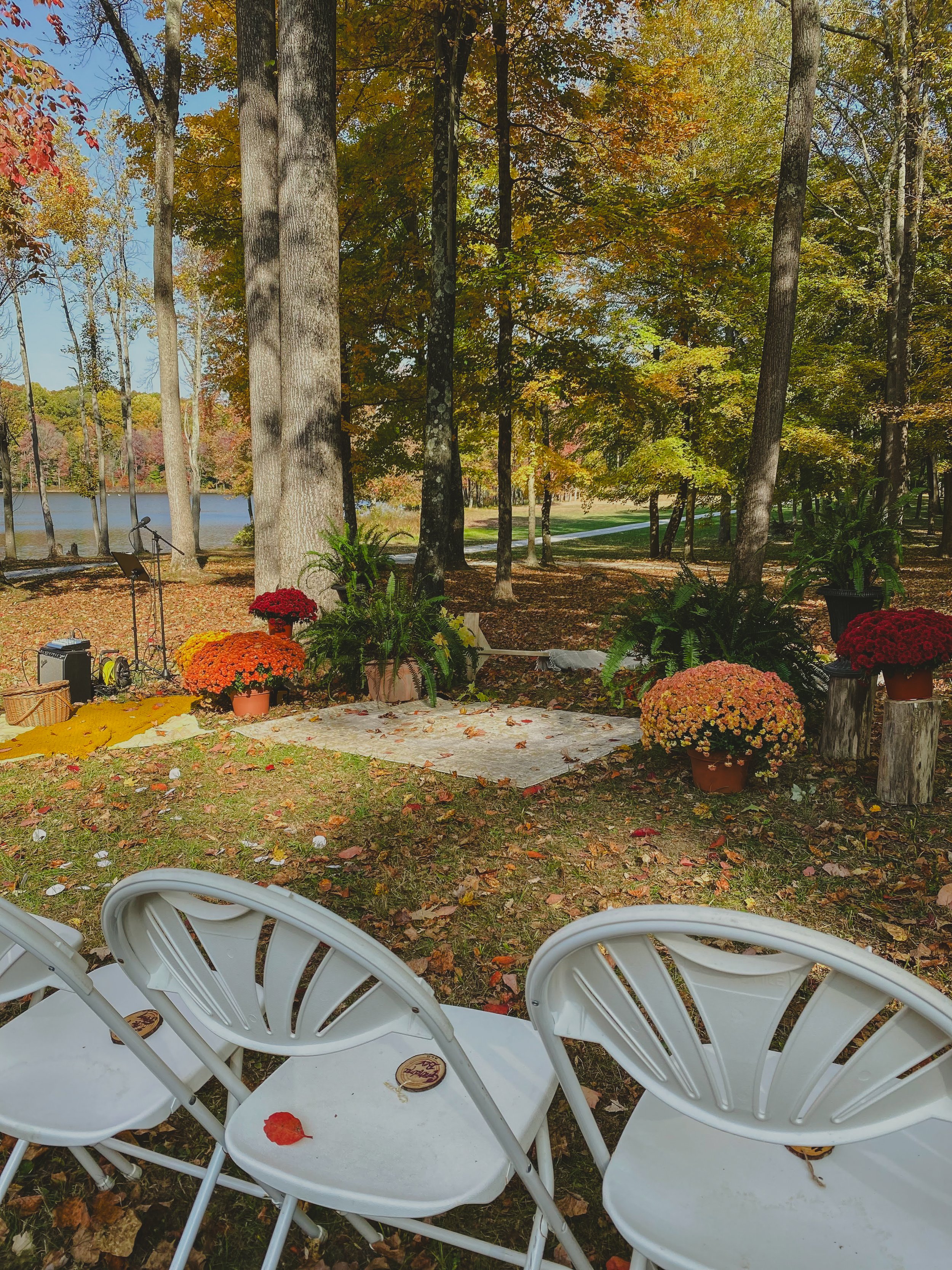 Outdoor stage set up with flowers, trees, and chairs in autumn