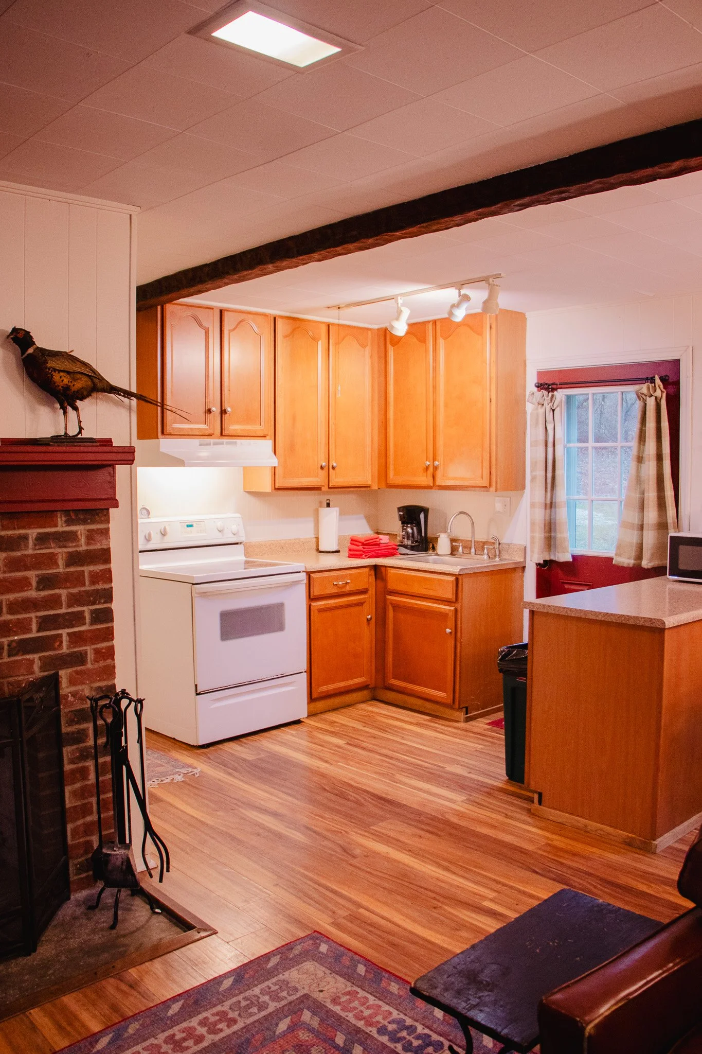 Kitchen with wooden cabinets, white stove, and window with curtains.