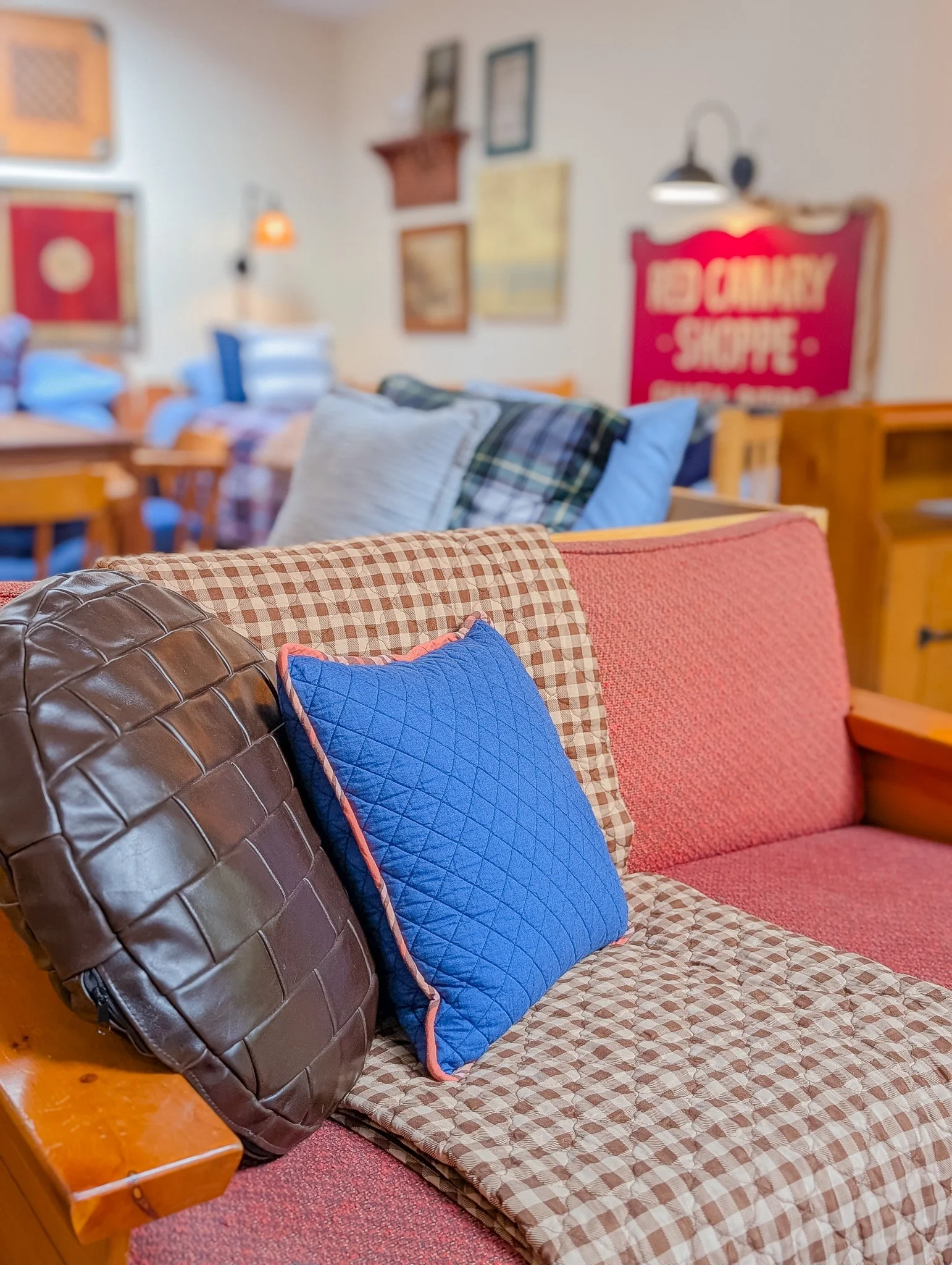 Interior of a furniture store or showroom with various sofas, pillows, and framed artwork on the walls.