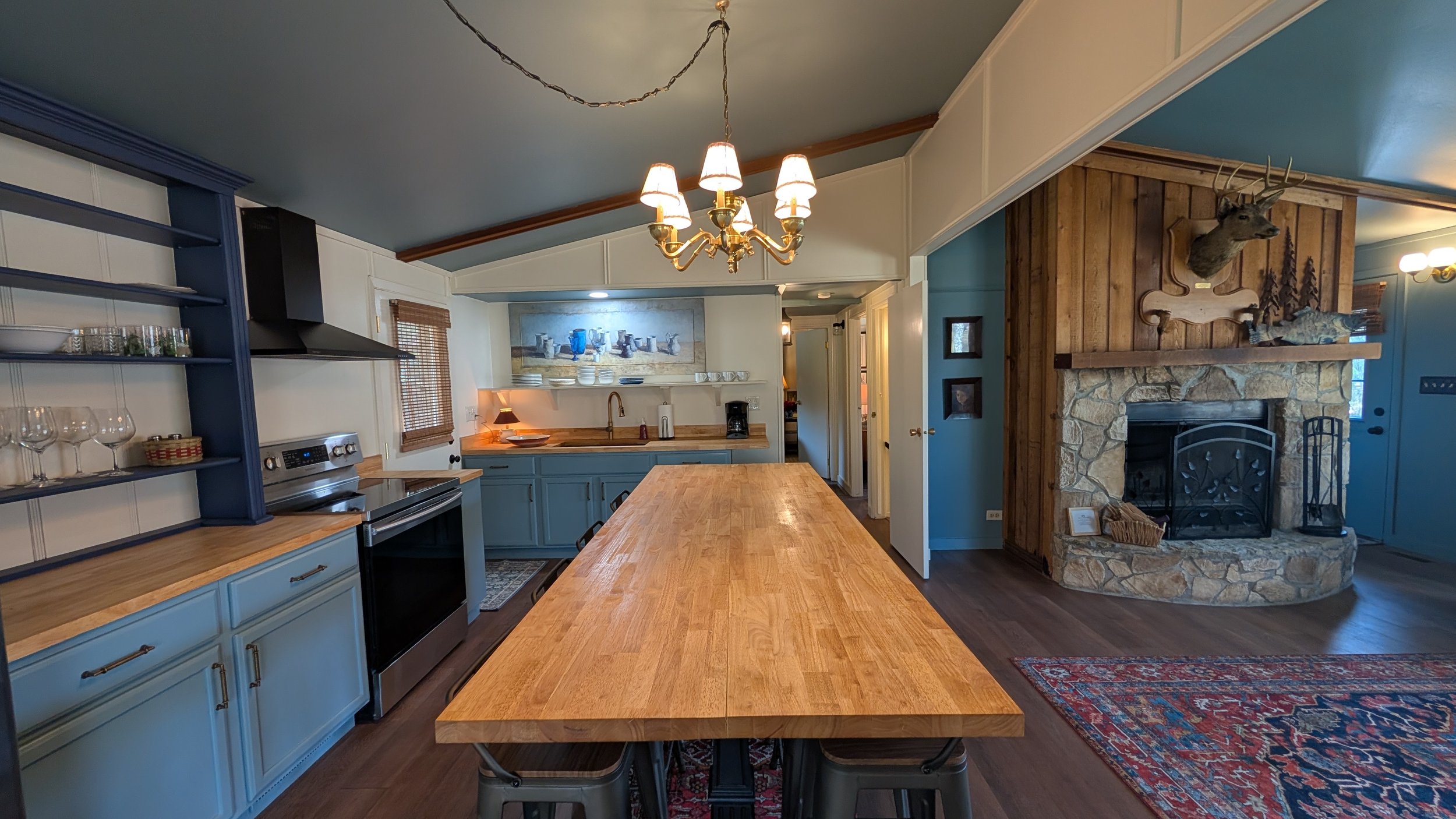 Open plan living room and kitchen. Large, counter height butcher-block table for dining and meal prep.