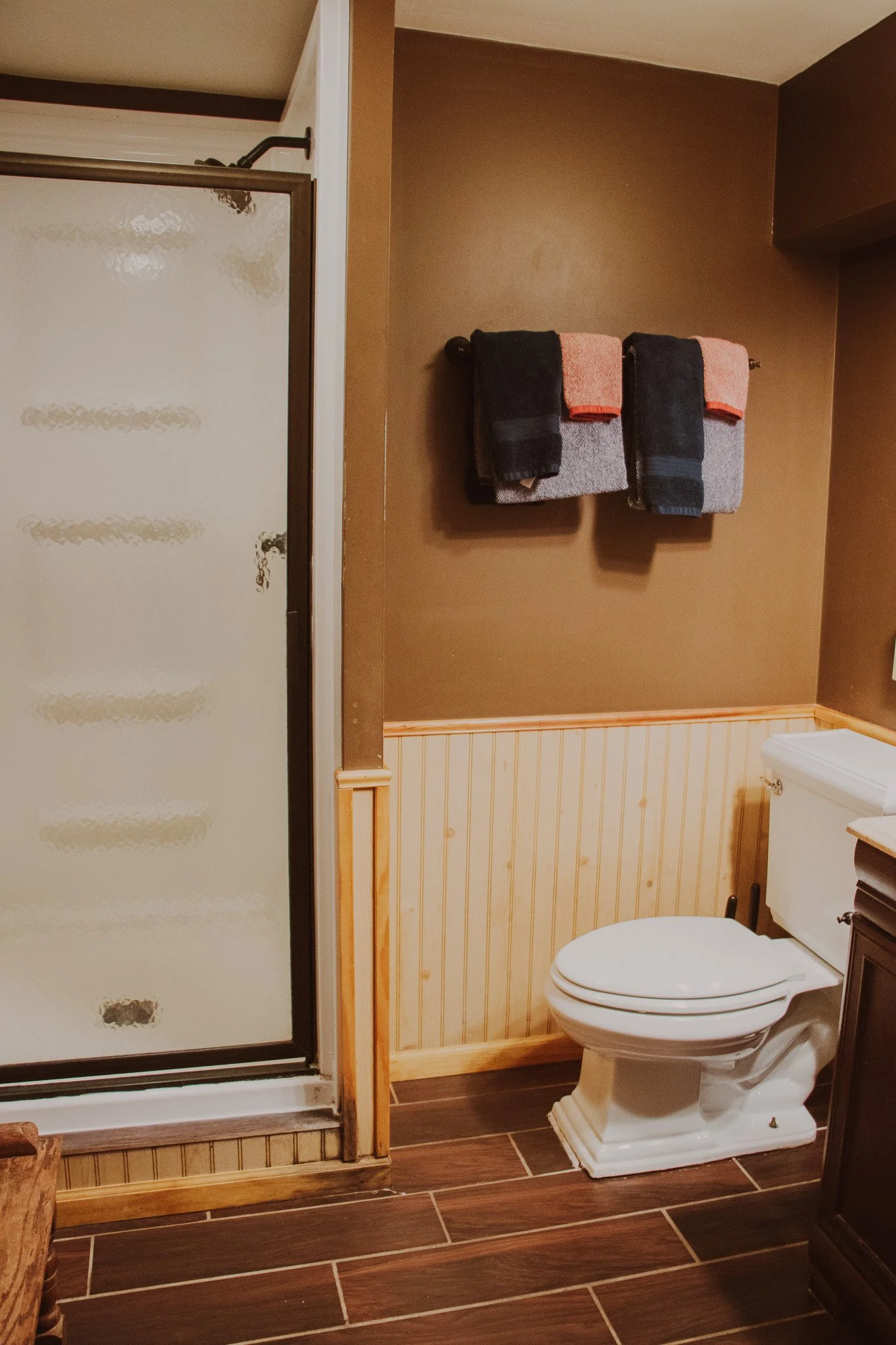 Bathroom with a shower stall, a toilet, and a wall-mounted towel rack with folded towels.