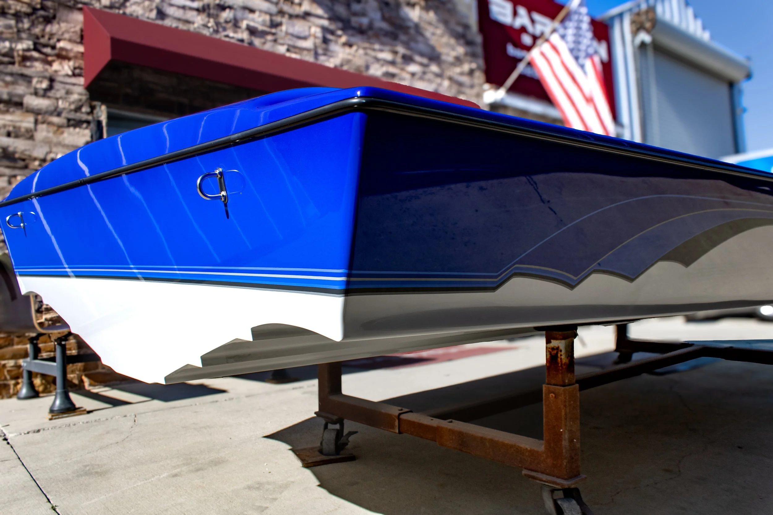 A blue and white boat on a wooden stand outdoors, with US flags in the background.