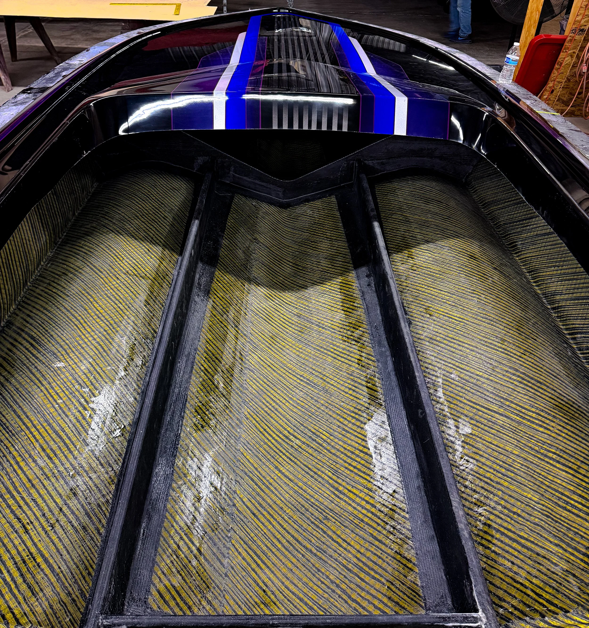 A boat hull with a black body, blue and white racing stripes