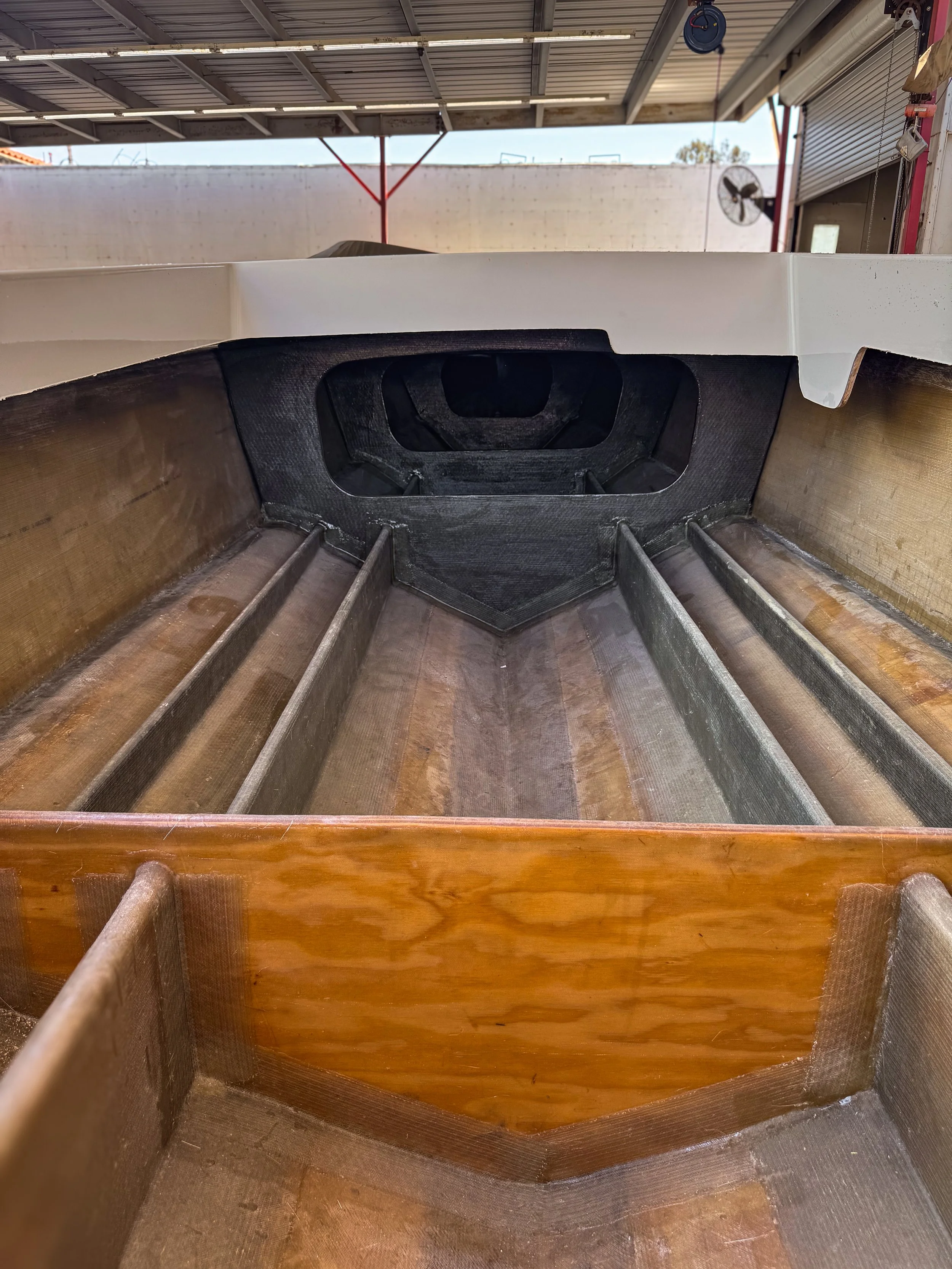 Inside of a boat hull showing the wooden exterior and keel, with an open section revealing the interior structure.