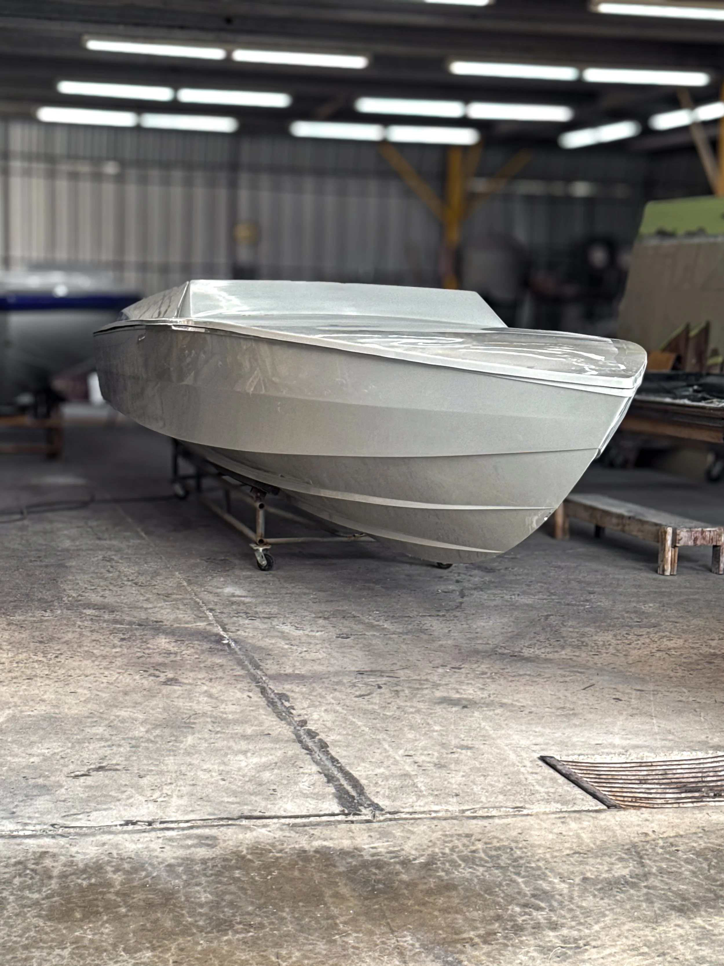 A boat covered with a white tarp in a warehouse or storage area.