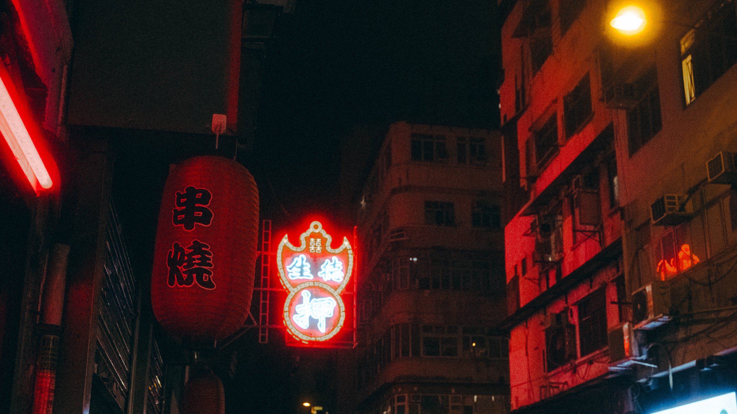 Calles de una zona urbana con letreros en neón en chino y faroles rojos iluminados en la noche.