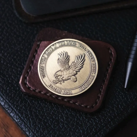 Gold coin with a flying eagle, placed on a leather patch, on a black textured surface.