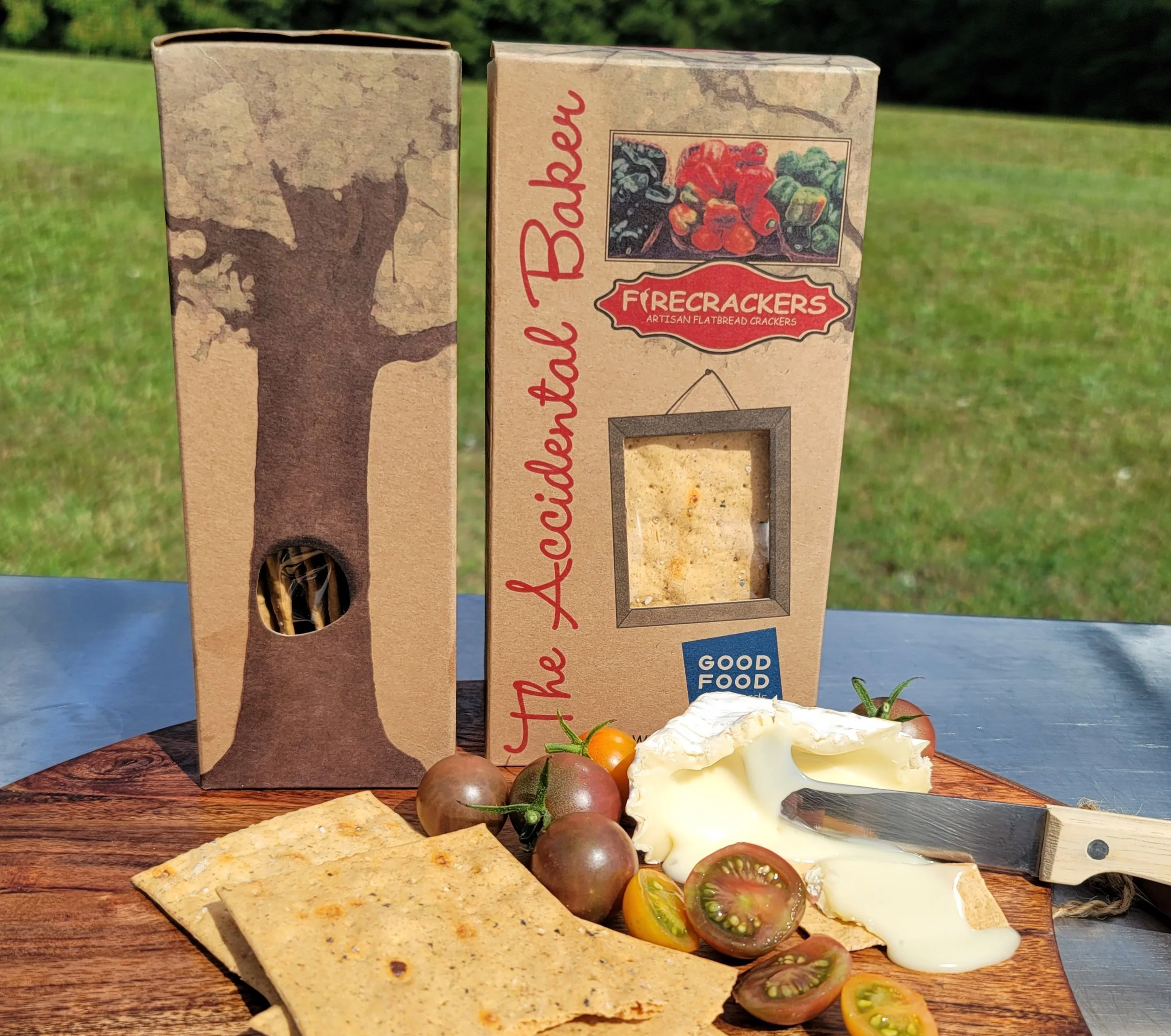 Close-up of spicy Firecracker artisan flatbread crackers with cheese, heirloom tomatoes, and crackers on a charcuterie board at a picnic.