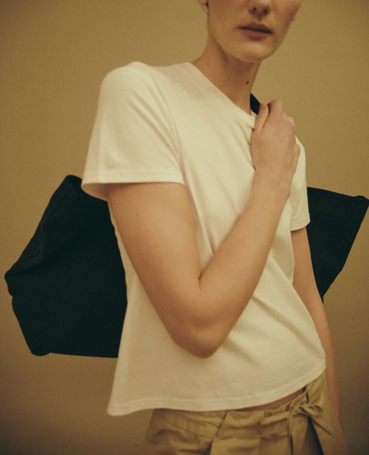 Image of a person wearing a t-shirt and carrying a bag.