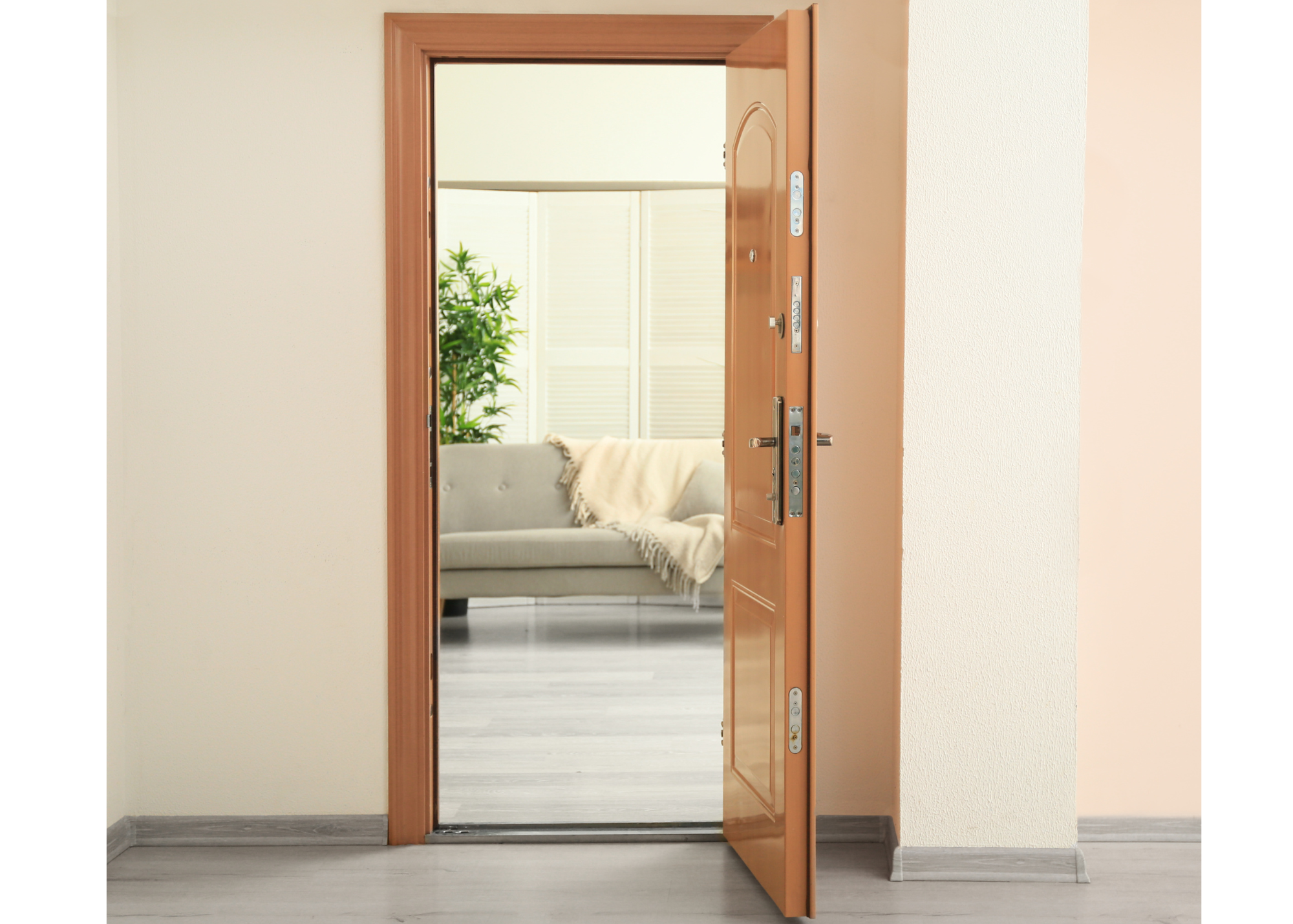 Open wooden door leading into a living room with a gray sofa and a large green plant, illuminated by natural light from windows with white blinds.
