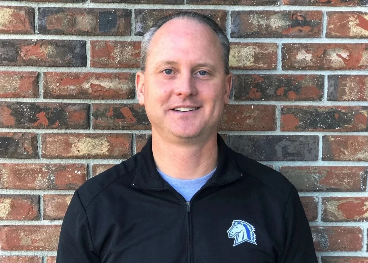 Aaron Flaug - Partner - Arise Ventures - Photo of Aaron smiling at the camera in front of a brick wall..