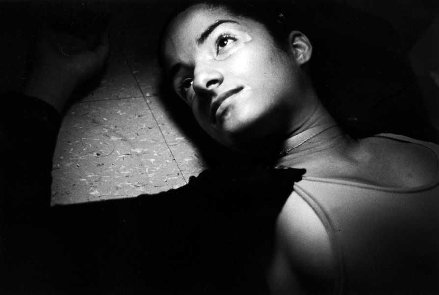 A woman lying on the floor, looking up, with her head turned to the side, in black and white.