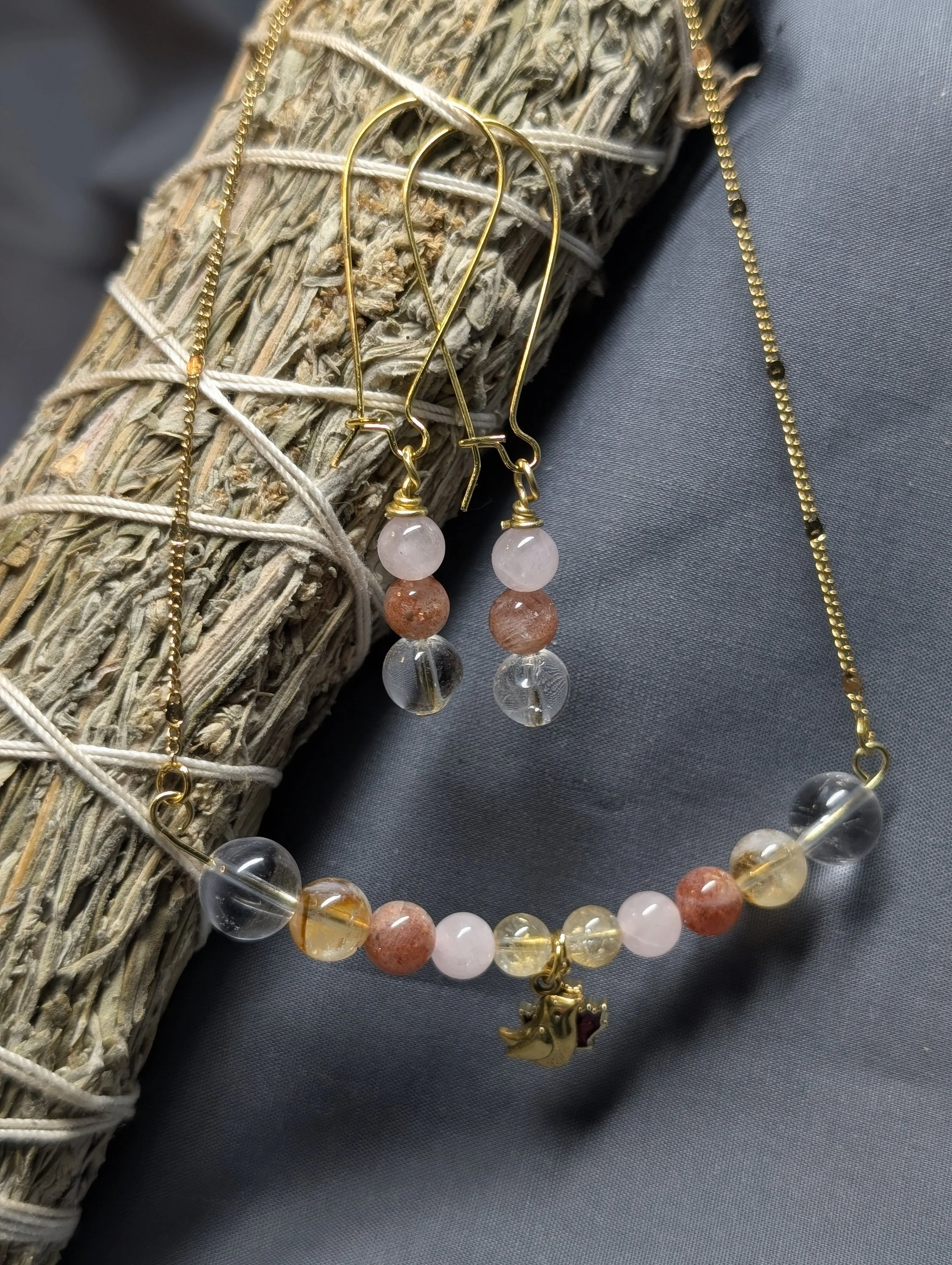 Necklace and earring set with clear quartz, citrine, sunstone, rose quartz, and a goal bird pendant and a red leaf pendant. 