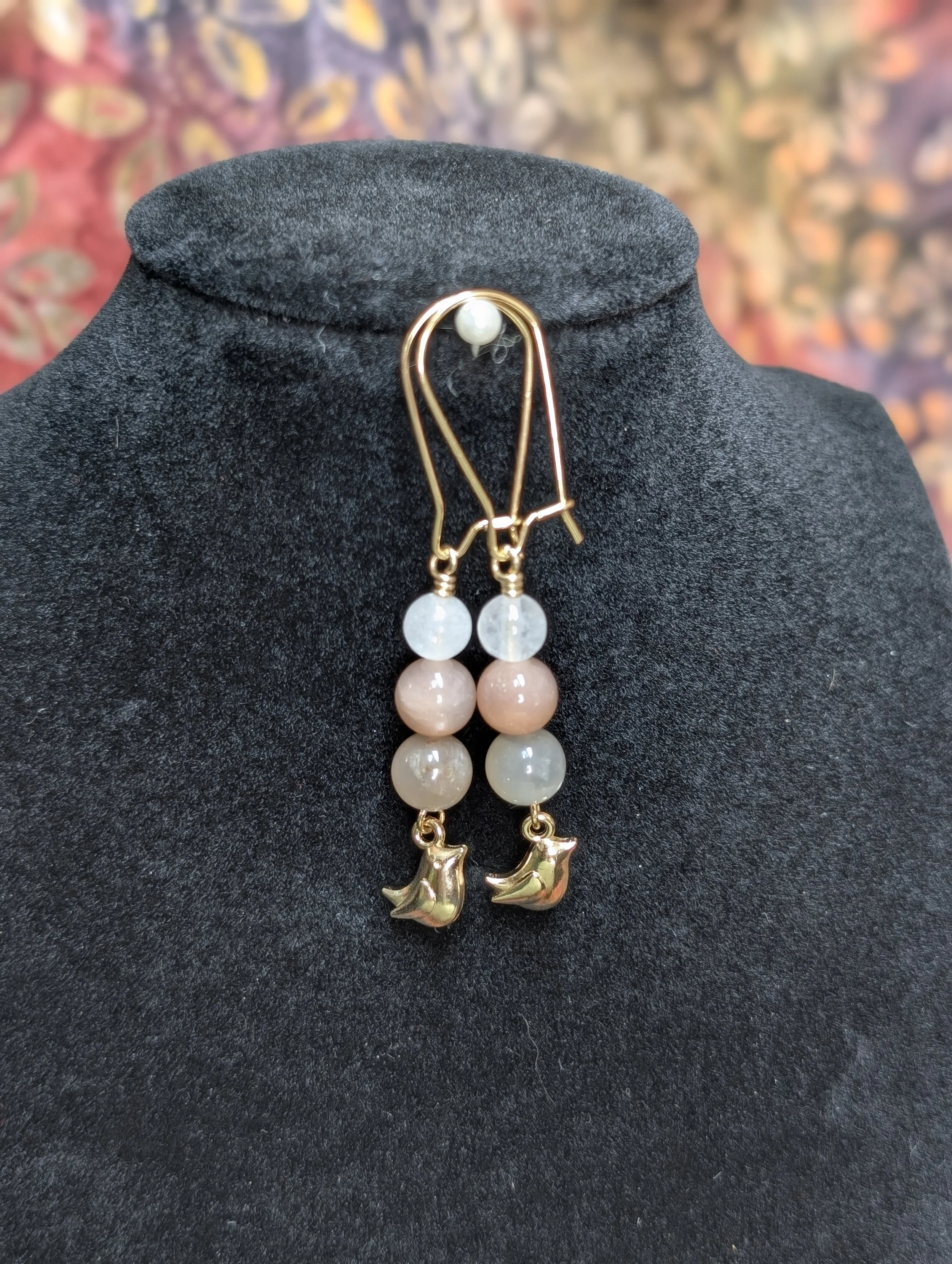 Gold earrings with white jade, peach moonstone, and moonstone. Bird charms