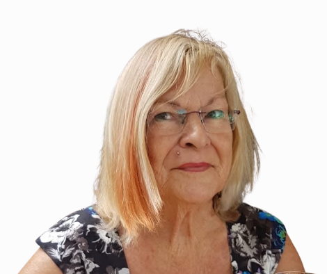 A portrait of an older woman with shoulder-length blonde hair, glasses, and a floral top, looking at the camera against a white background.