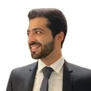 A man in a suit smiling and looking to the side.