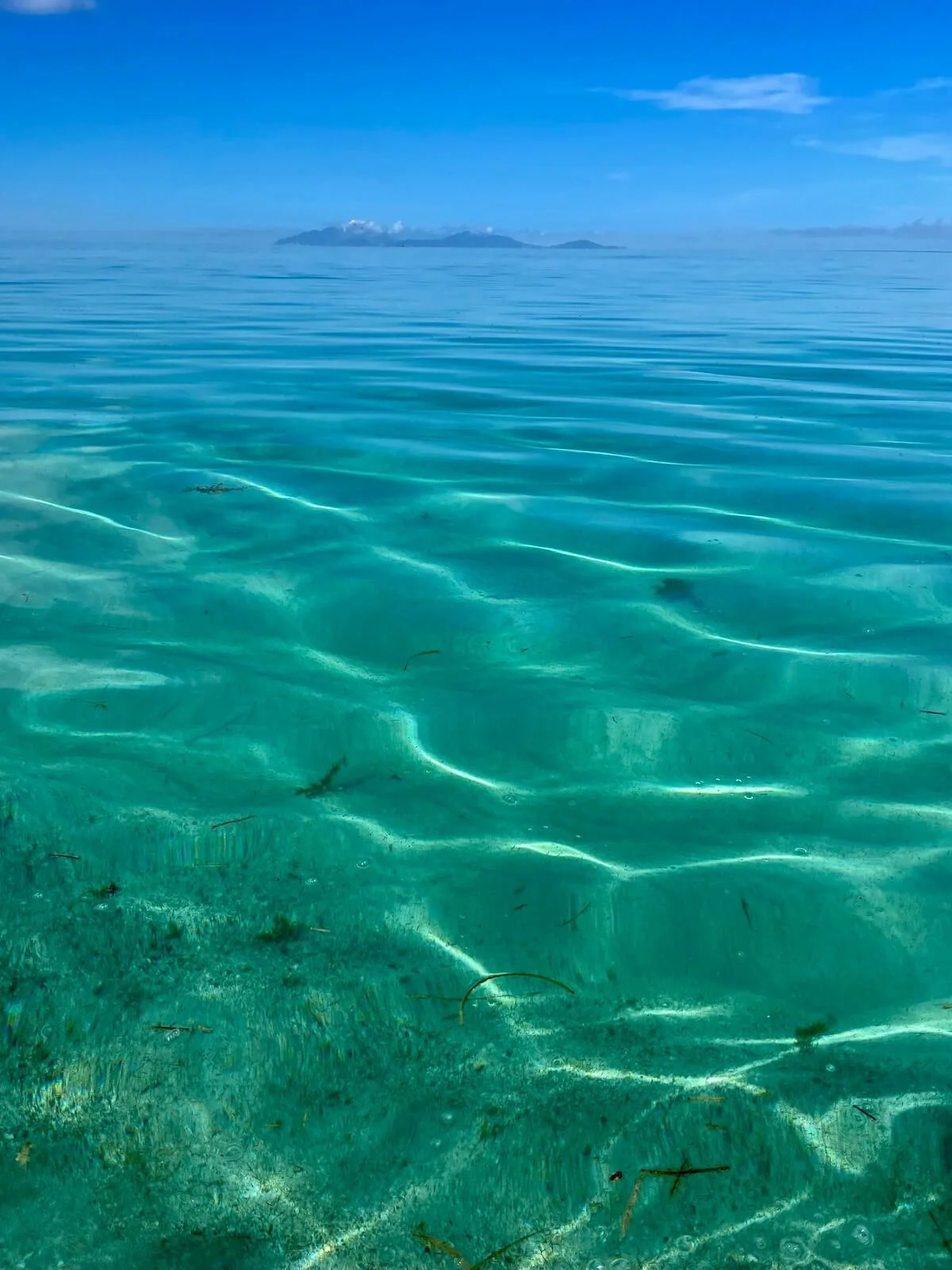 Crystal clear turquoise water at Crabbe Hill Beach with a view of Monserrat in the distance and sunlight shooting along the ocean floor, the home of The Sea Change Retreat with Kat to design your new era with the inspiration of the Caribbean Sea.