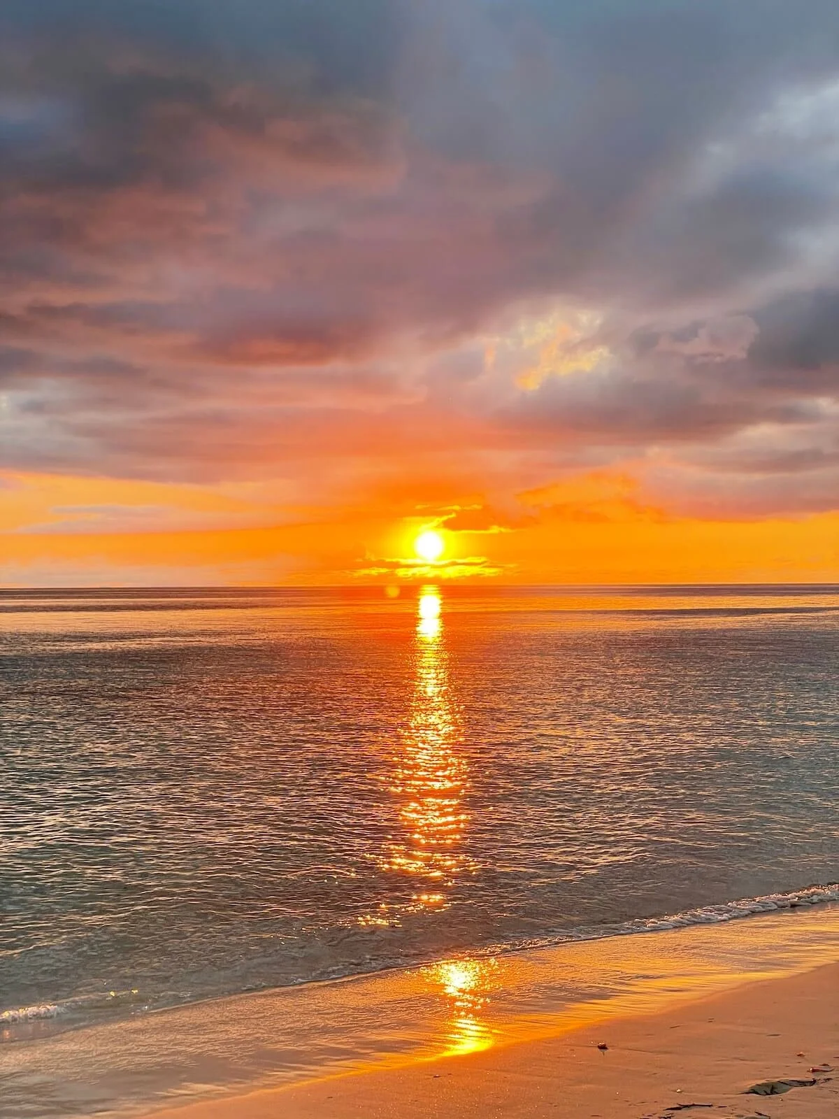 A Crabbe Hill Beach Sunset over the calm Caribbean Sea with orange and purple sky, the home of The Sea Change Retreat in Antigua with Kat Byles, space and time to listen and receive clarity inspiration and alignment with your new era.