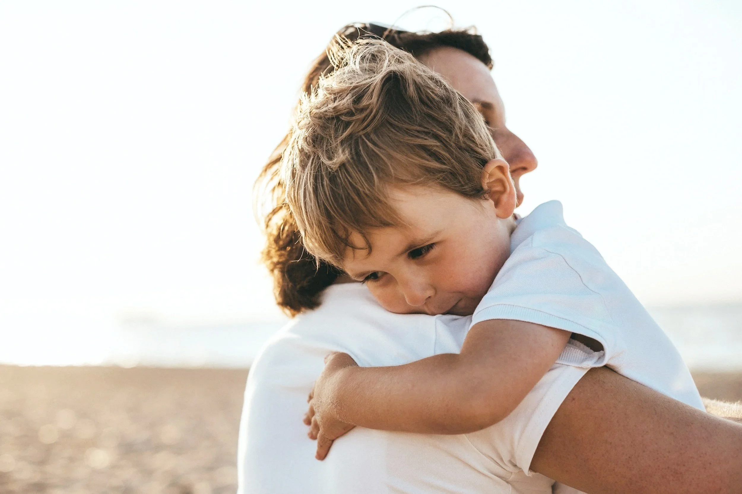 Child hugging parent on a beach at sunset — symbolizing family bonds and the trusted care GoodMaids professionals bring to every household.