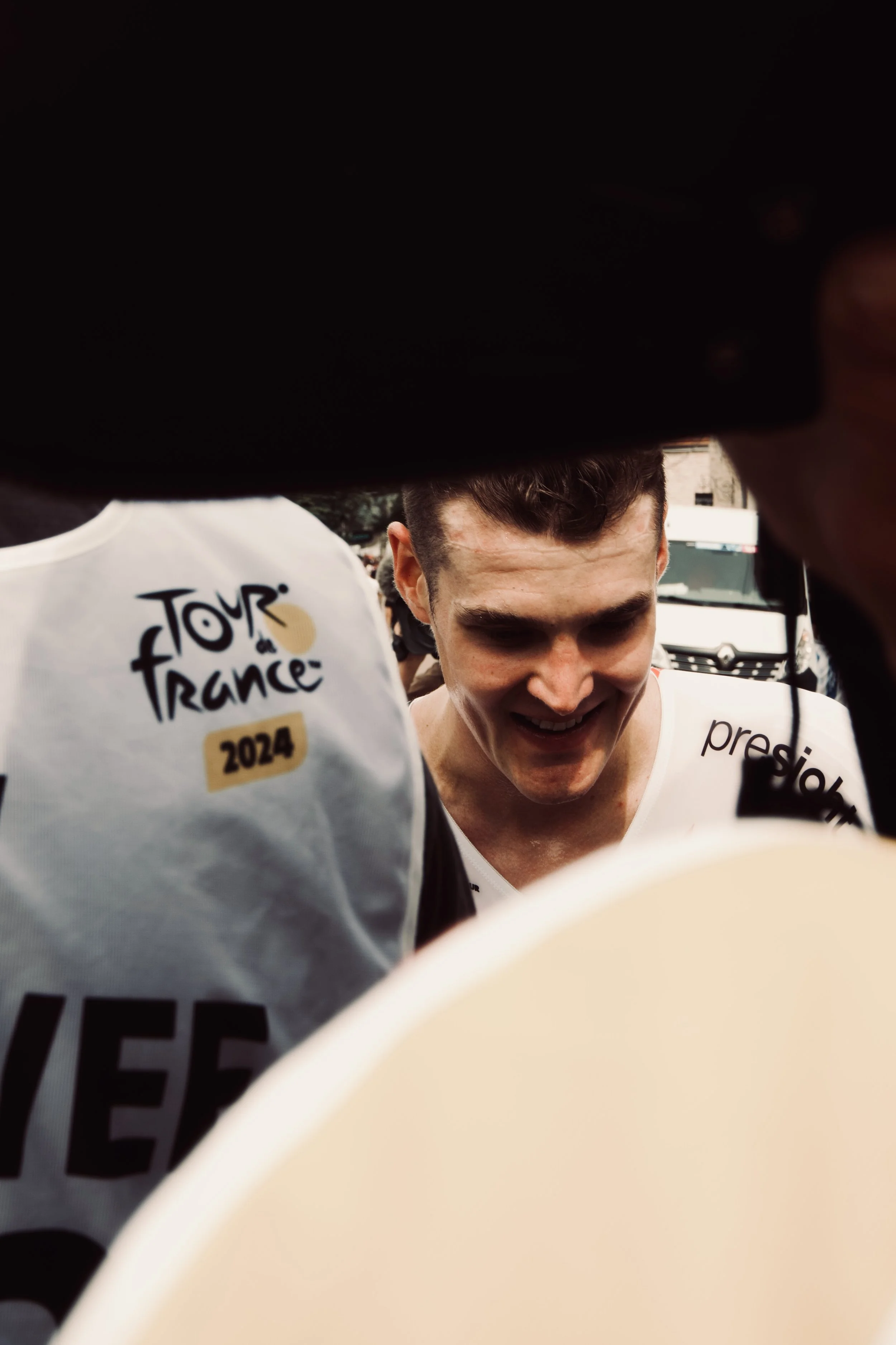 Cycliste souriant lors du Tour de France 2024, entouré de plusieurs personnes