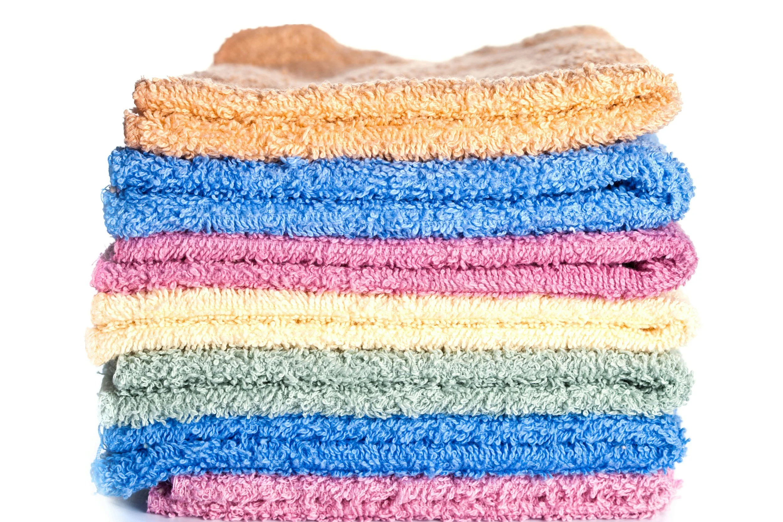 Stack of colorful folded towels in peach, blue, pink, cream, green, and darker pink.
