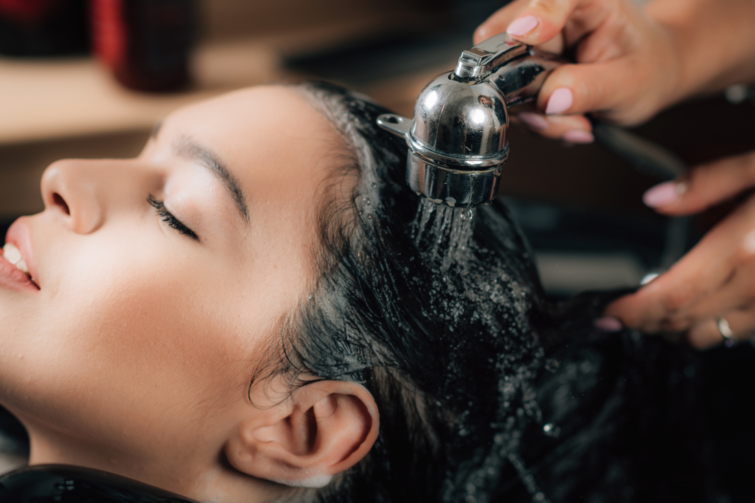 Woman receiving a water-based hair treatment at a salon