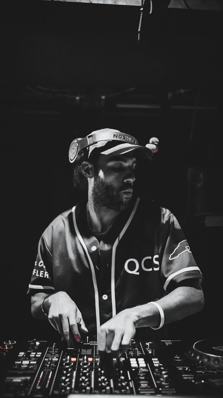 Black and white photo of a DJ wearing a hat and shirt in charlotte NC at a club