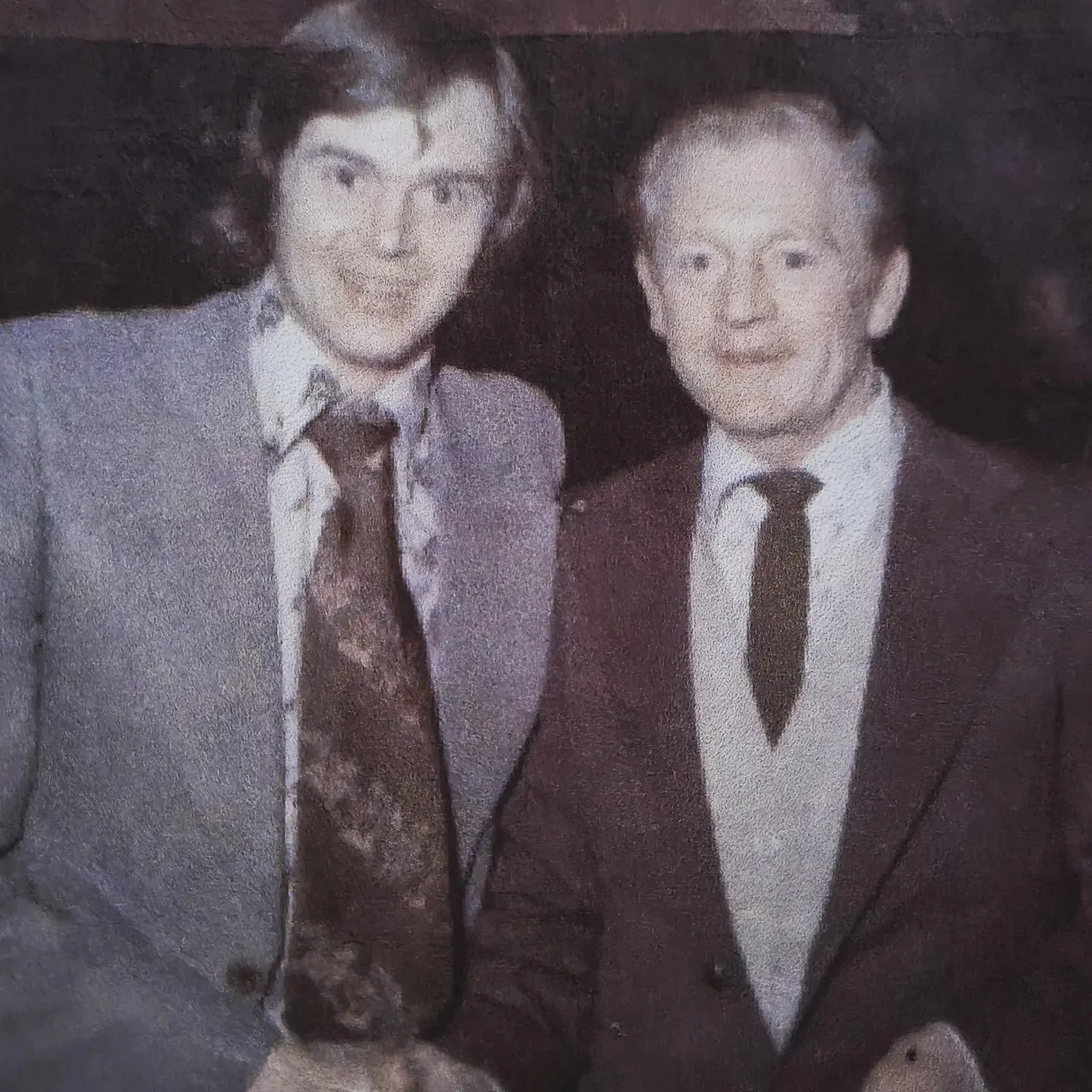 A black and white photo of a man and woman dressed in formal attire, standing close together, smiling at the camera.
