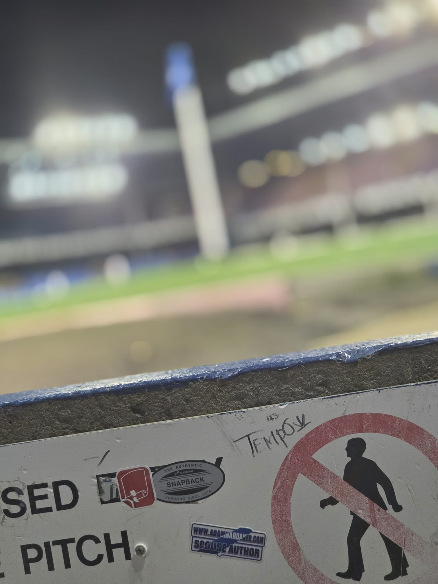 A close-up of a sign with multiple stickers, including a 'Scout Author' sticker, text in Russian, and a no-smoking symbol featuring a person smoking with a prohibition sign over it. The sign appears to be attached to a metallic or plastic surface.