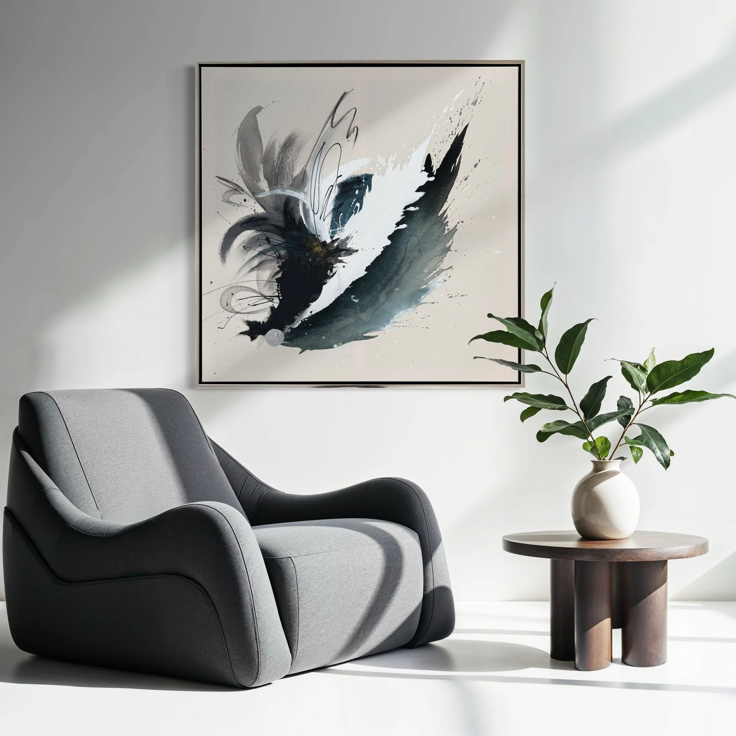 Ein moderner grauer Sessel neben einem kleinen runden Holztisch mit einer weißen Vase und grünen Blättern, über dem ein abstraktes schwarz-weiße Kunstwerk hängt.