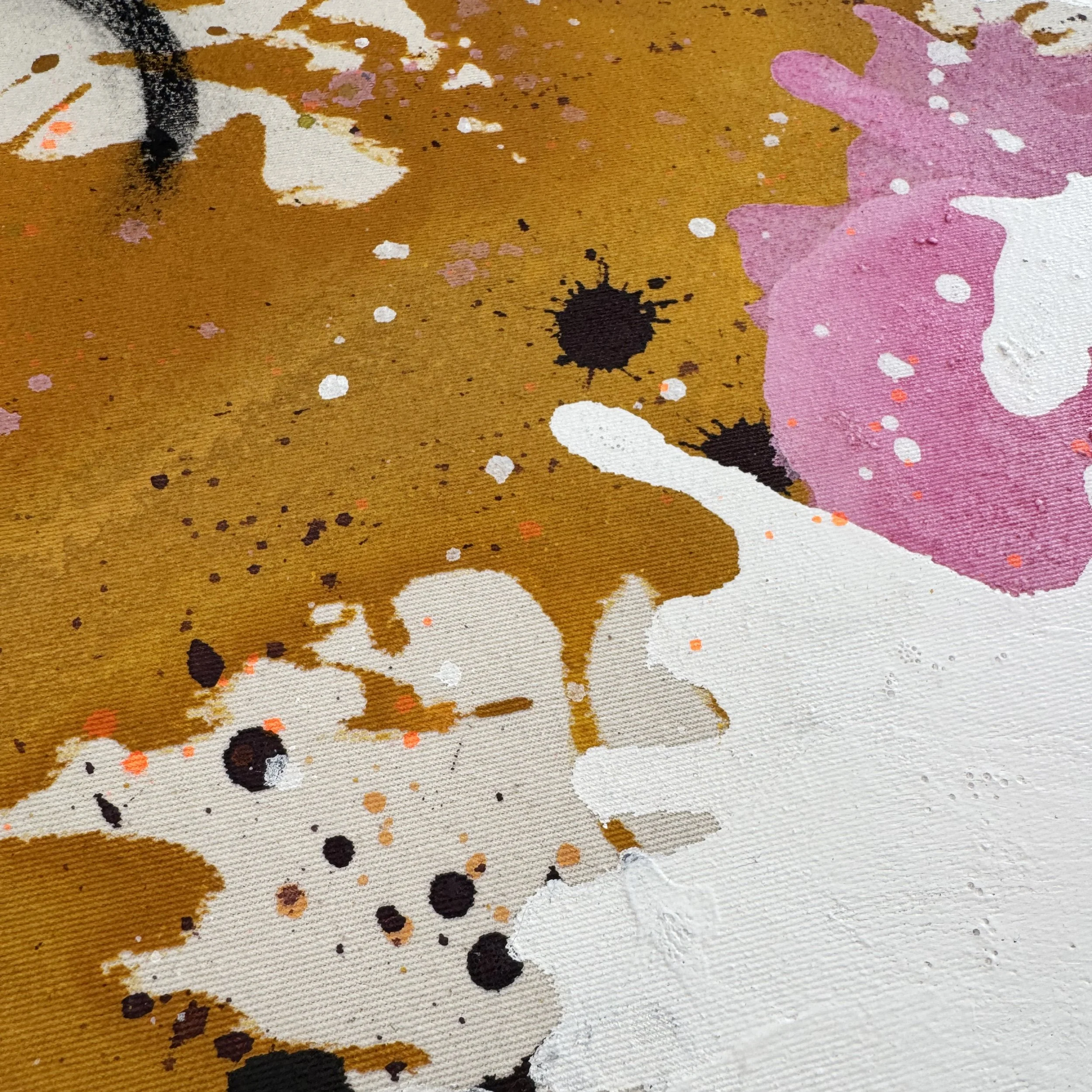 Nahaufnahme eines abstrakten Gemäldes mit Farbspritzern in Gold, Schwarz, Weiß, Rosa und Lila.