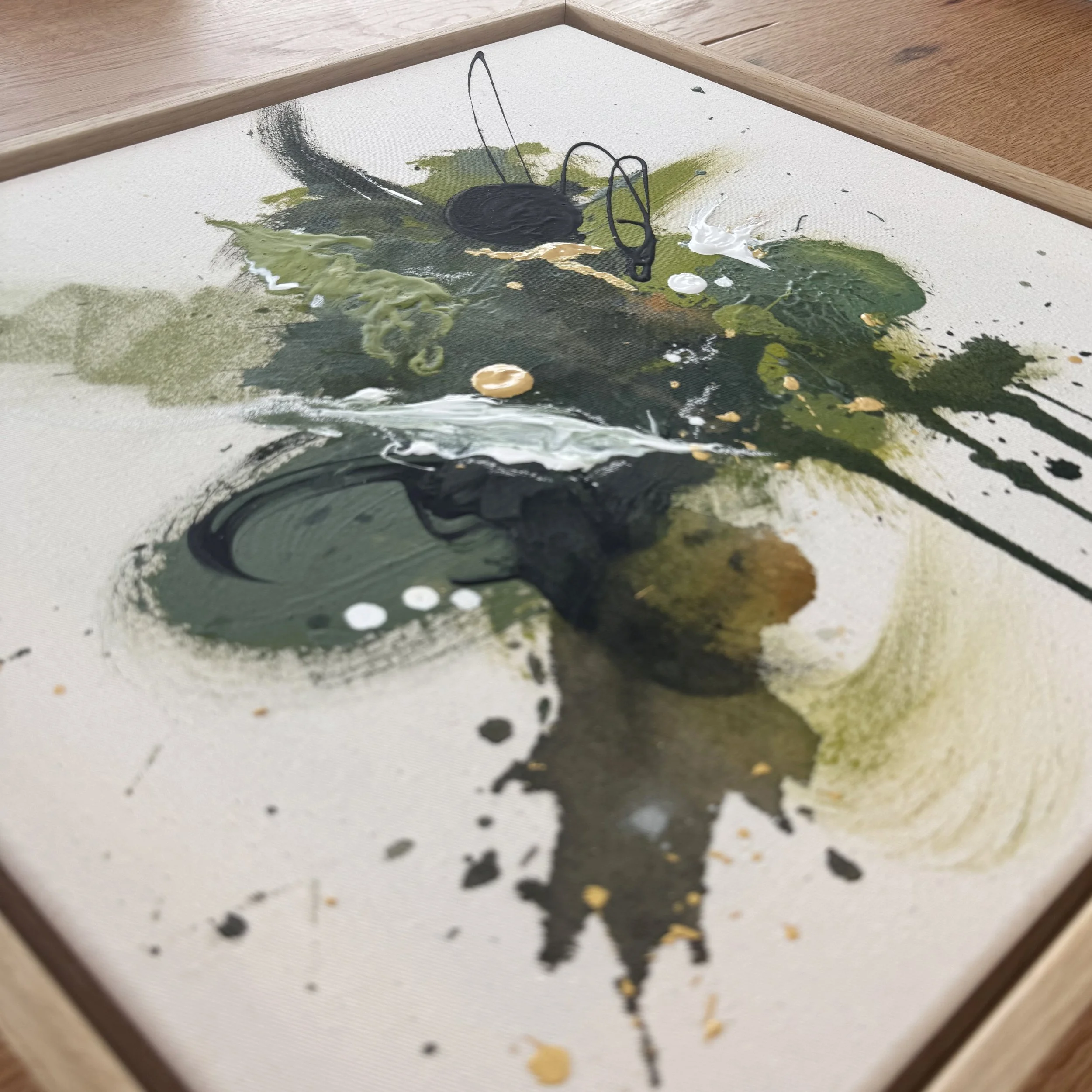 Abstraktes Gemälde mit dunklen, grünen, weißen und gelben Farbklecksen auf einer Leinwand, gerahmt.