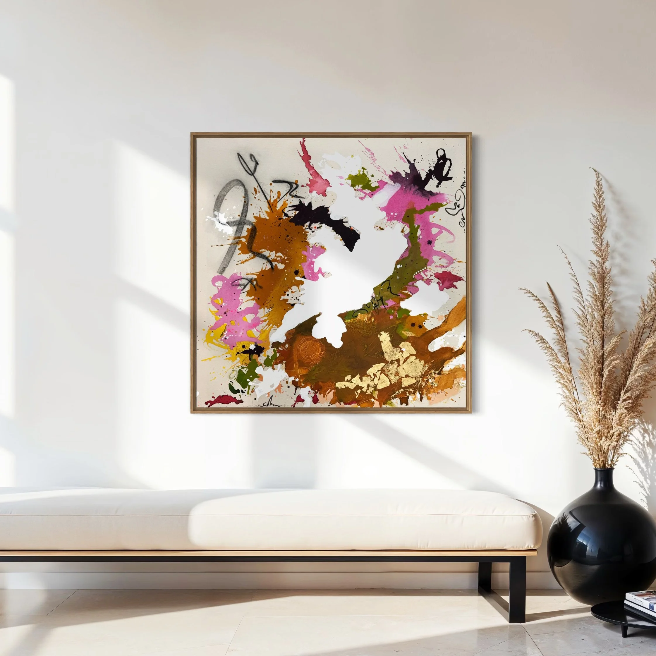 Abstraktes farbenfrohes Gemälde mit Spritzern und Pinselstrichen in Pink, Braun, Grün, Schwarz und Weiß, in einem Holzrahmen an einer weißen Wohnzimmerwand.