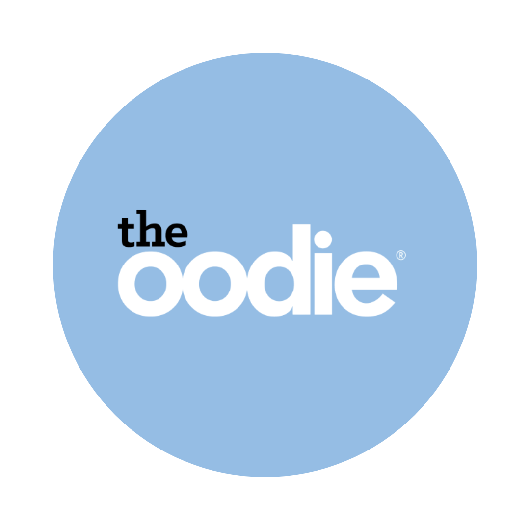 Logo for the Oodie with a light blue circular background and the words 'the oodie' in white and black text.