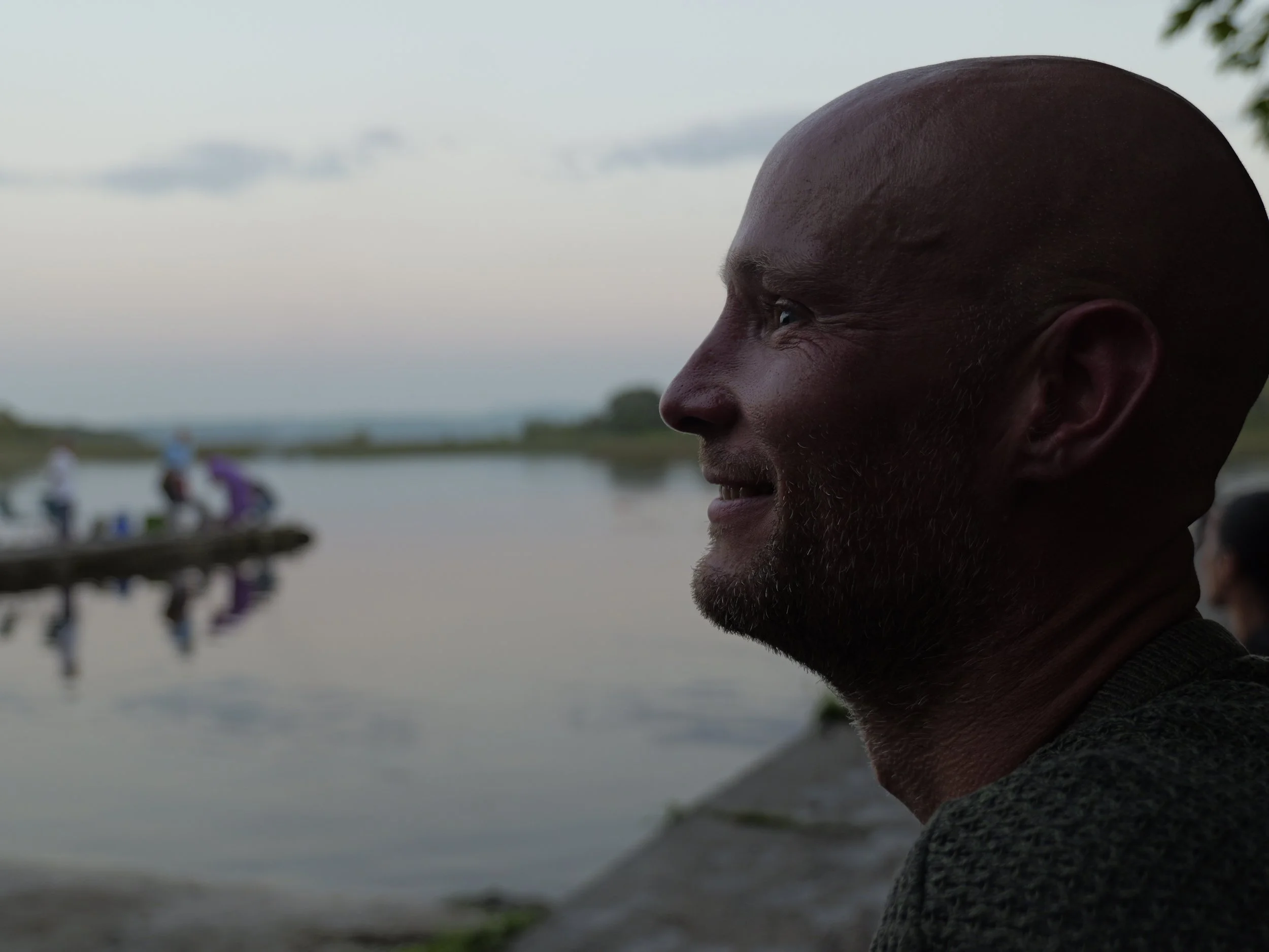 Geoff Brennan, holistic therapist and TRE® practitioner, standing peacefully by a lakeshore, reflecting connection between body, nature, and balance
