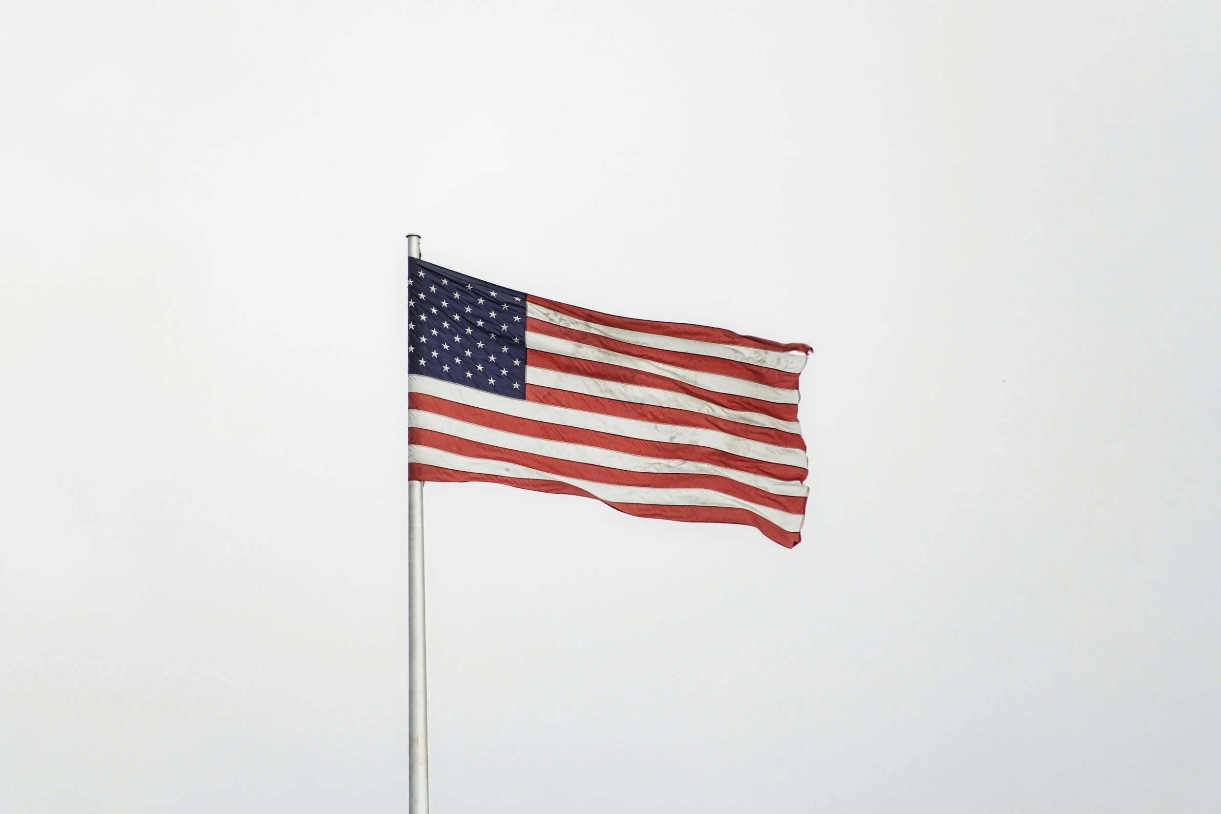 American flag waving in the wind against a cloudy sky.
