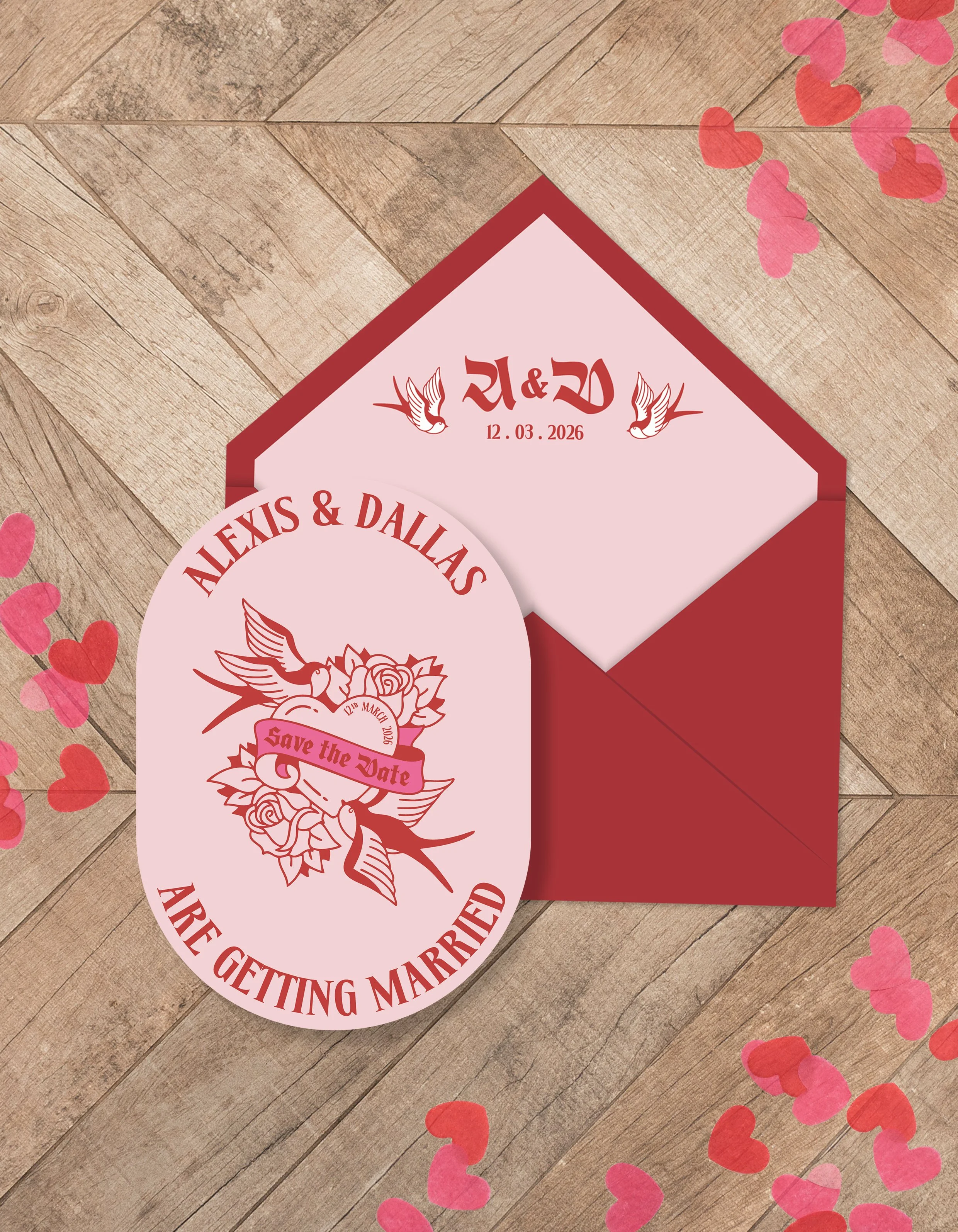 A romantic wedding invitation set with an oval 'Save the Date' card and a matching envelope, decorated with floral and bird motifs, placed on a wooden surface with scattered pink and red heart-shaped confetti.
