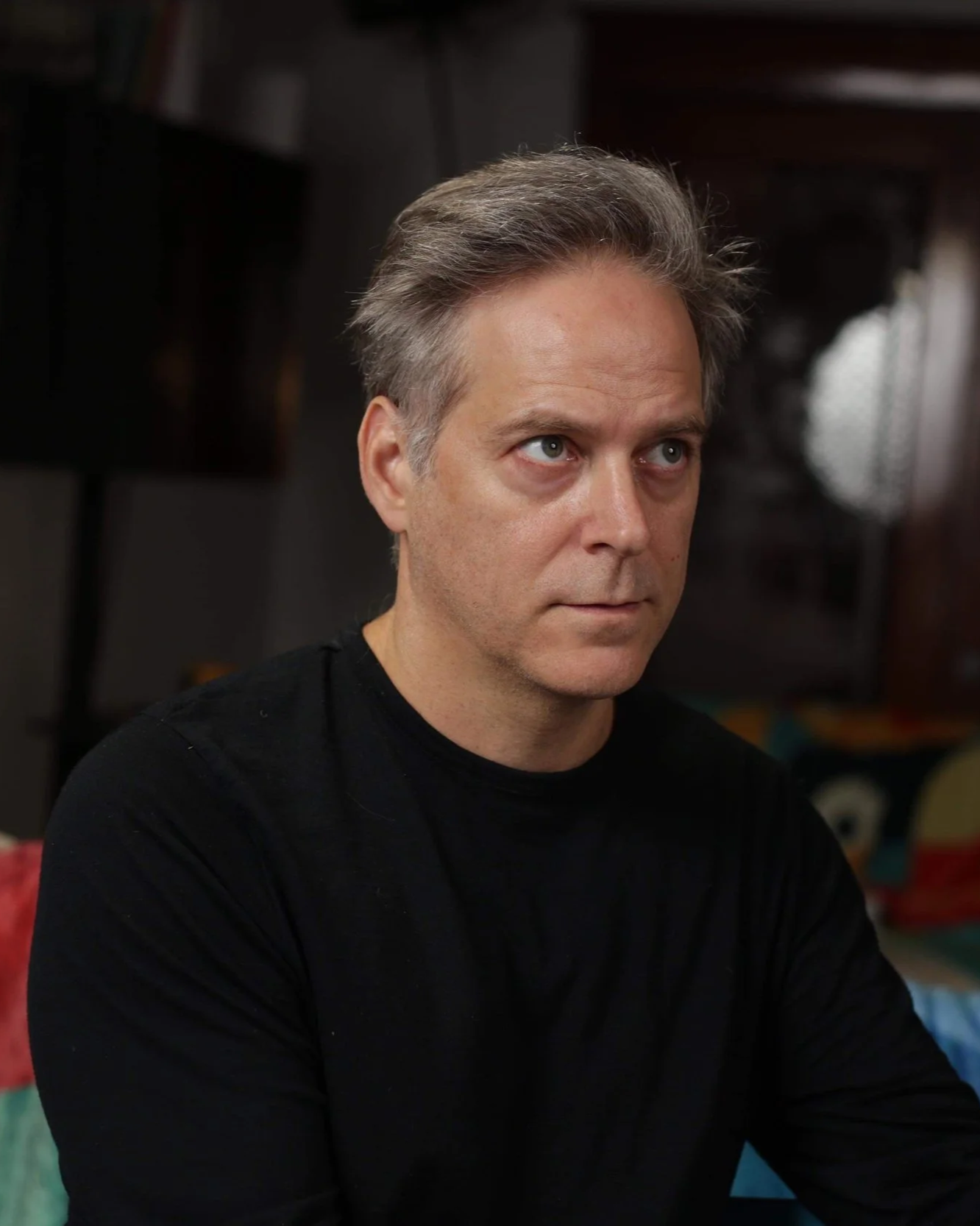 Daniel Parent, acteur, portant un t-shirt noir, regarde pensivement.