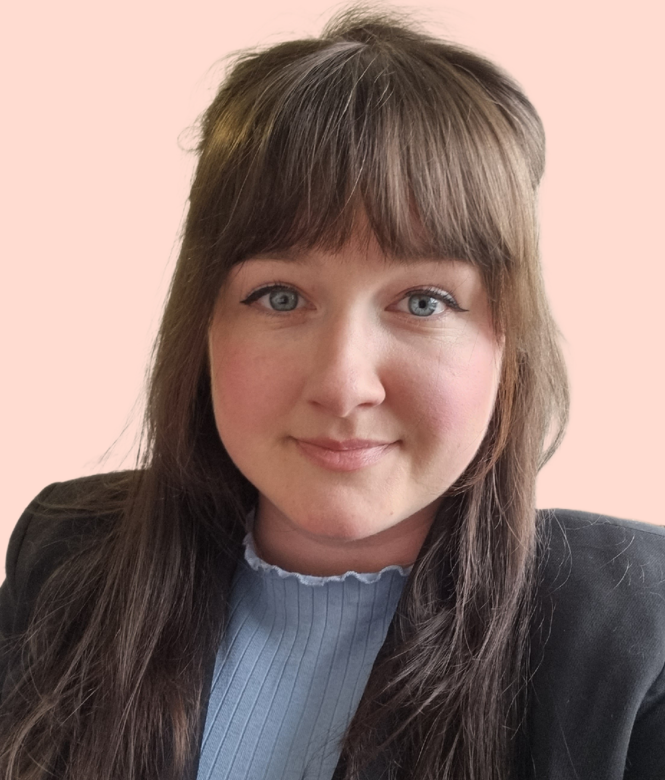 Close-up of a young woman with blue eyes, brown hair, and a subtle smile, wearing a light blue top and a black blazer against a pale pink background.