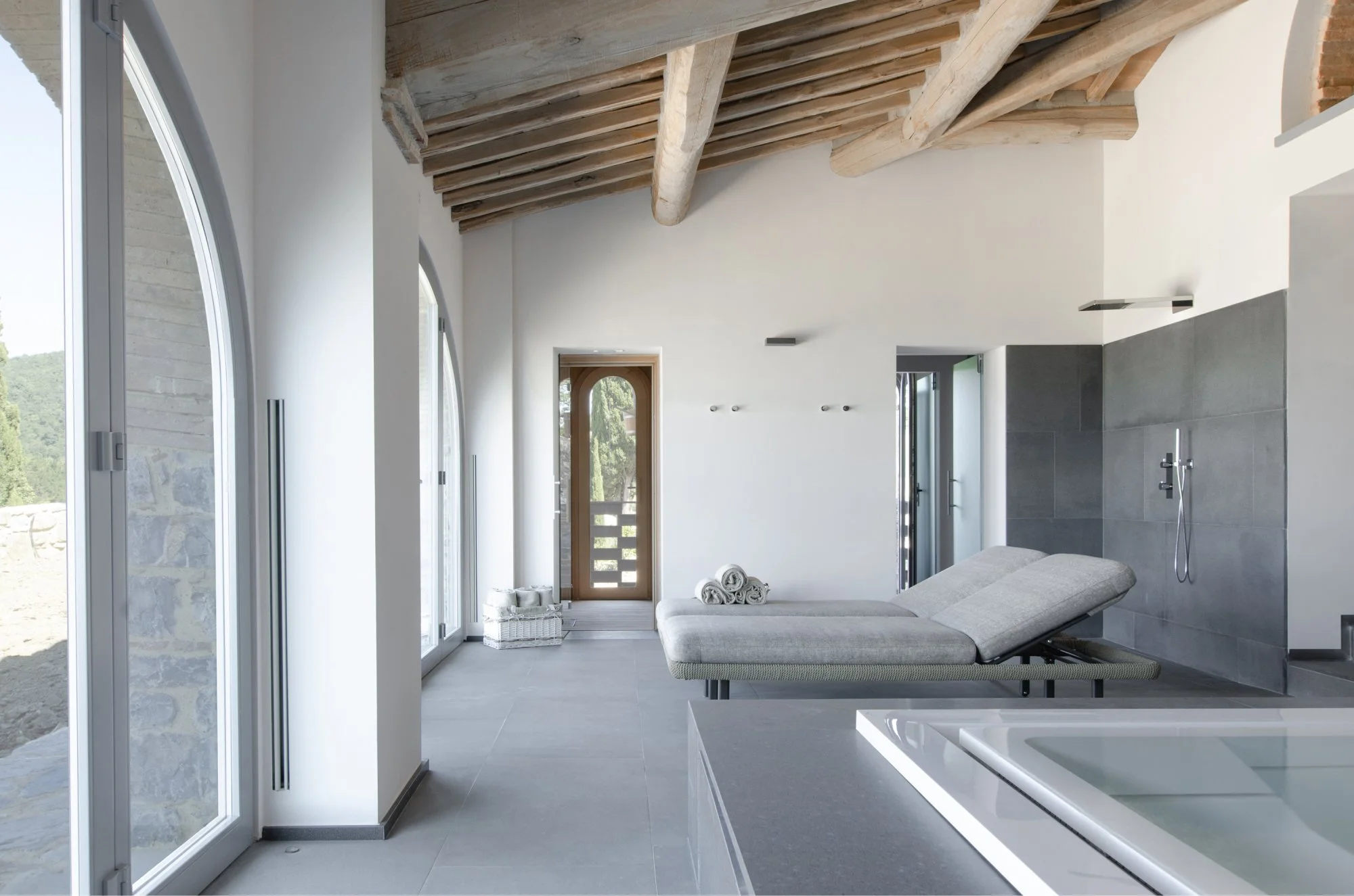 Interno di una spa o bagno con una chaise longue e vista su un balcone.