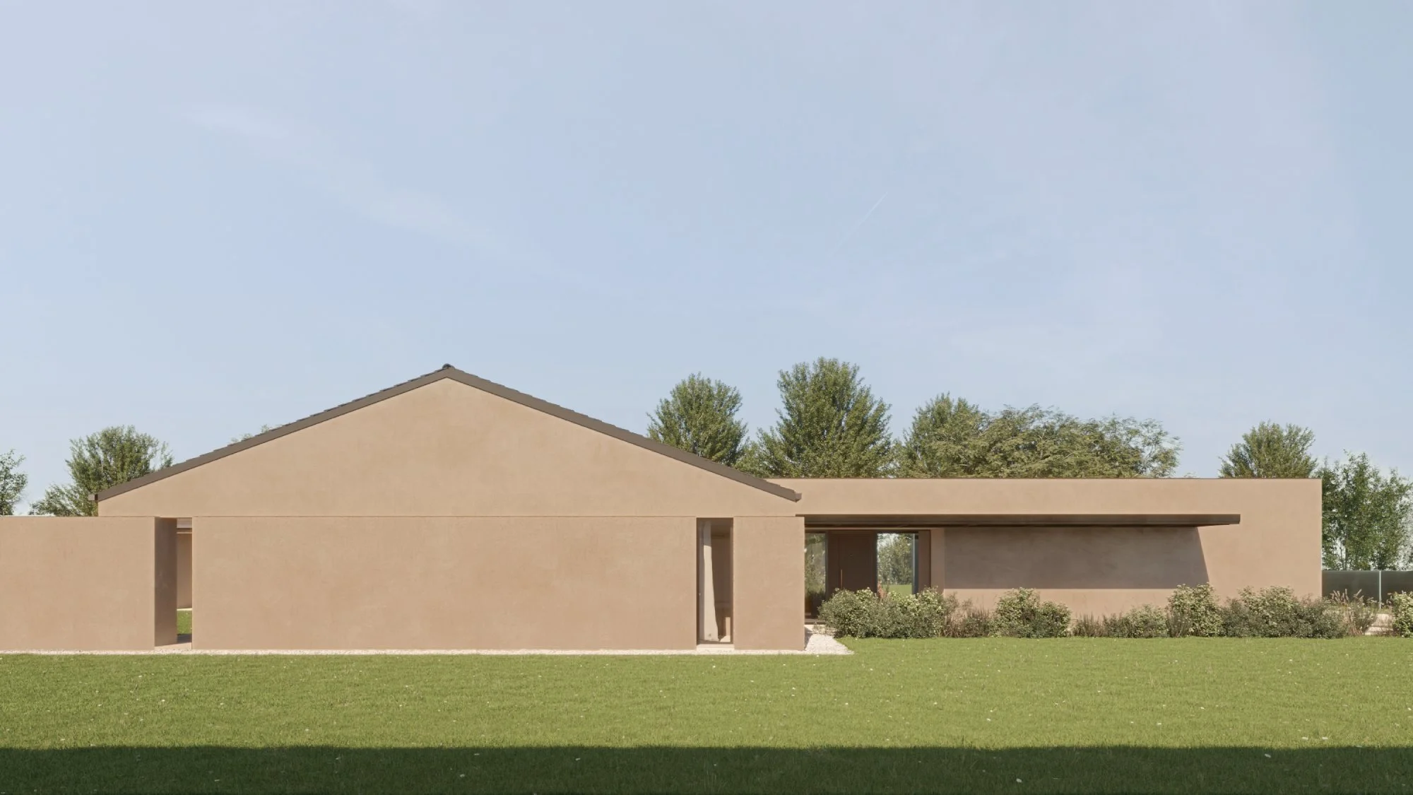 Edificio moderno con mura beige e tetto inclinato, contornato da arbusti e un prato verde, con alberi sullo sfondo sotto un cielo azzurro