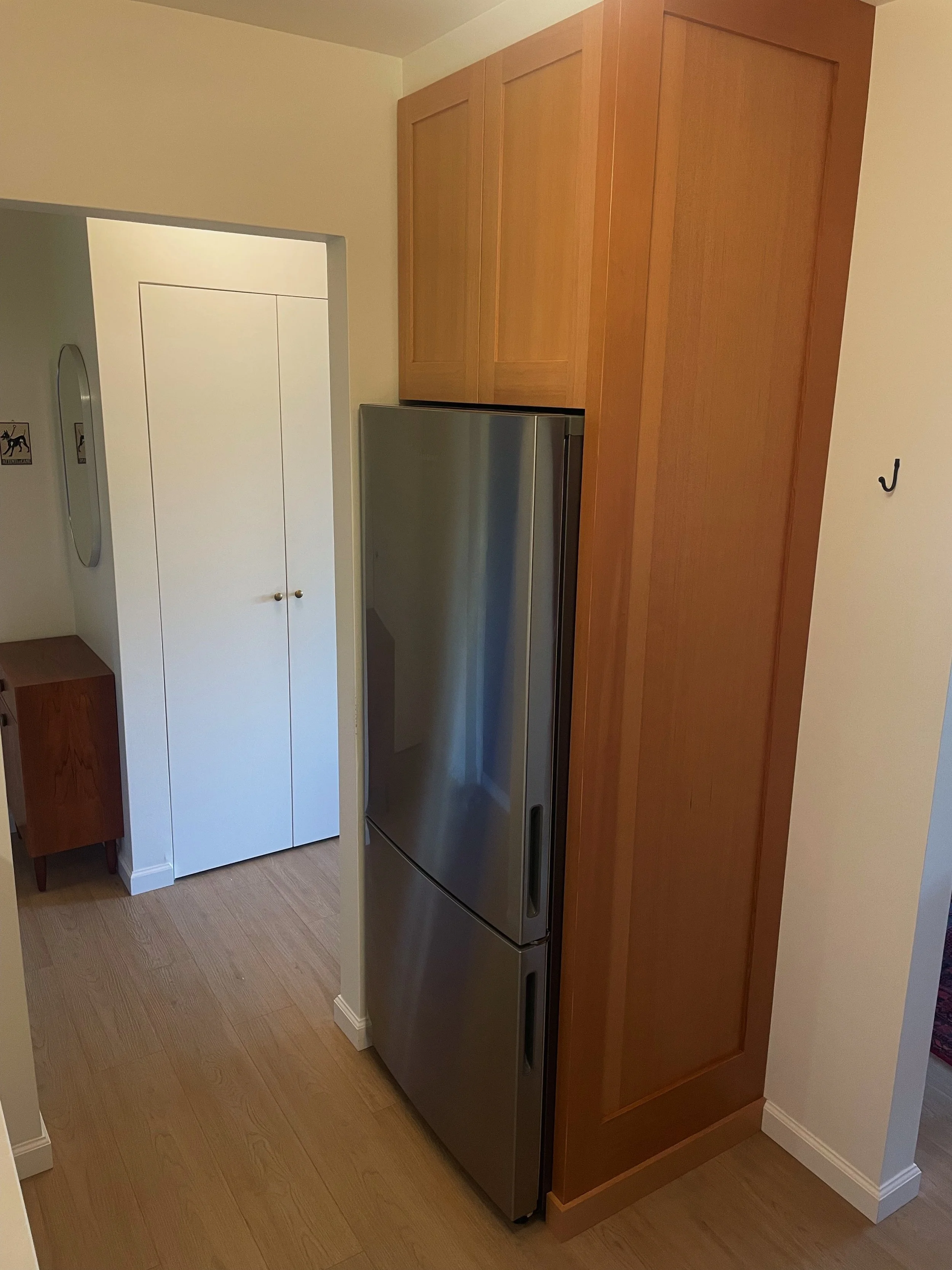 Stainless steel refrigerator surrounded by wooden cabinets in a kitchen.