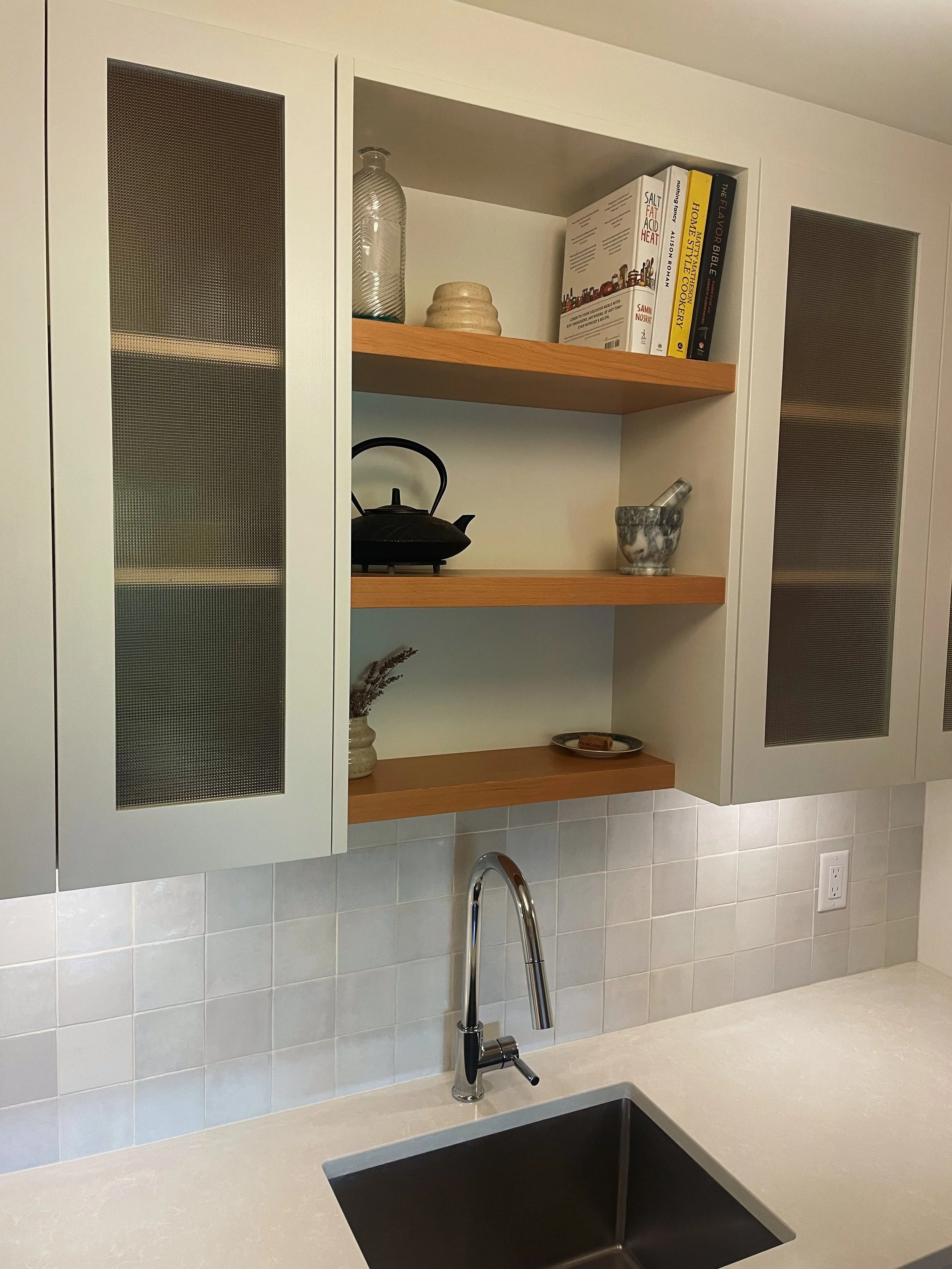 Kitchen with open cabinets, a countertop, a sink, and a backsplash with white tiles.
