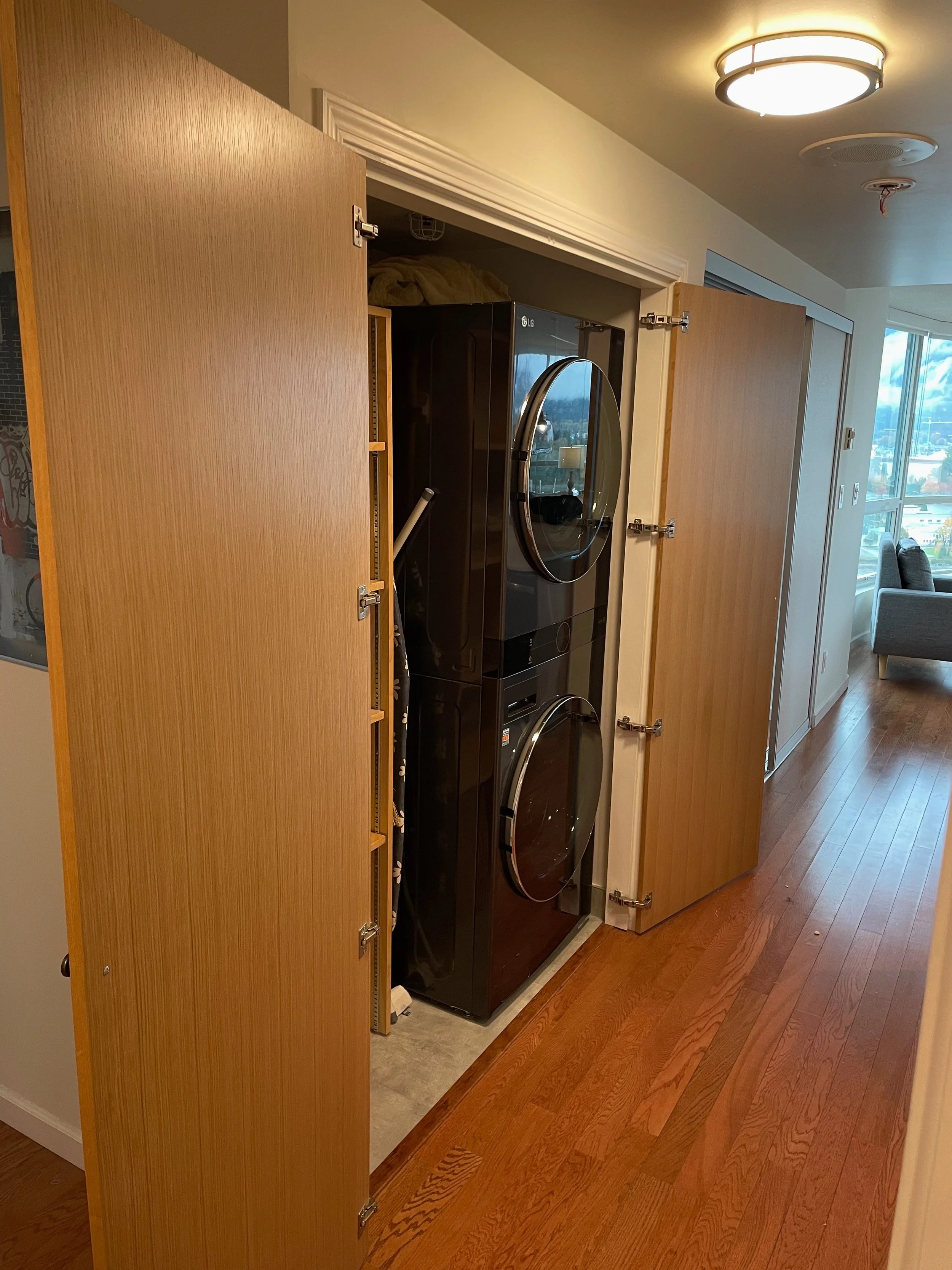 A closet with wooden sliding doors open, revealing a stacked washer and dryer in a laundry area inside a home.
