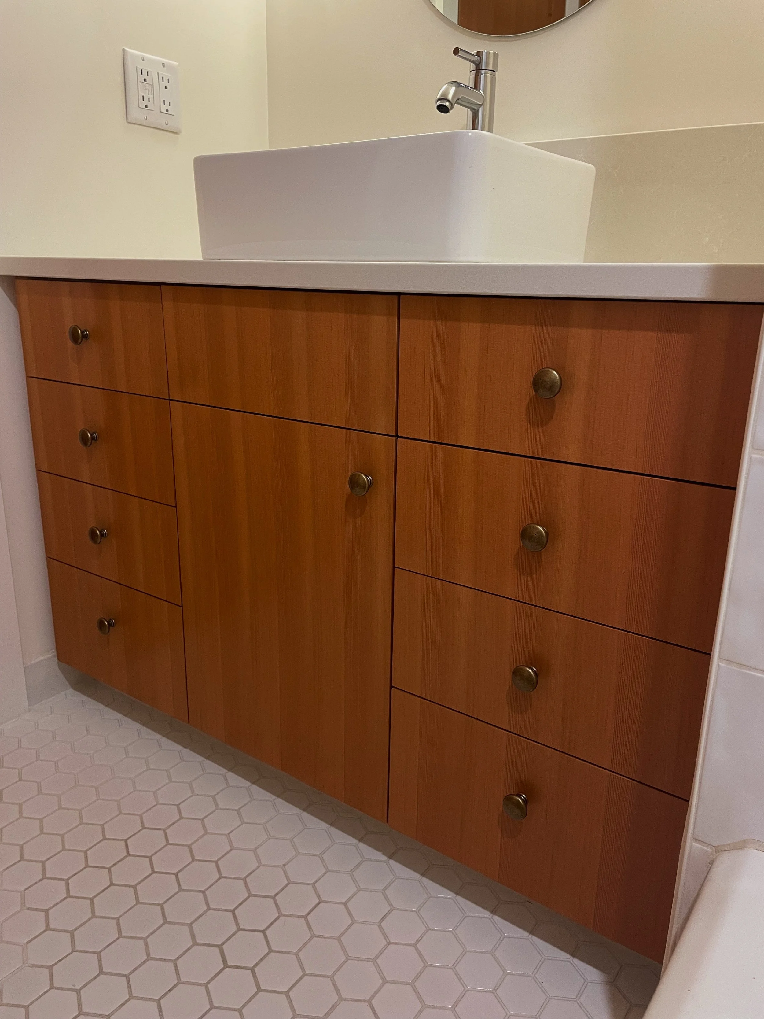 Bathroom vanity with wooden cabinet drawers, a white countertop with a square ceramic sink, and a modern metallic faucet.